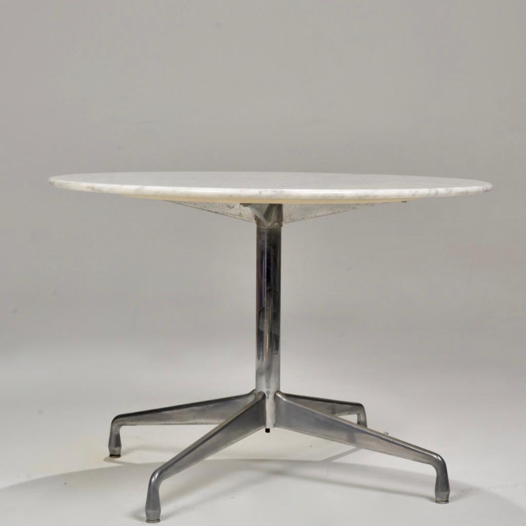 This Eames for Herman Miller dining table features a segmented aluminum base and a round Italian Carrara marble top.