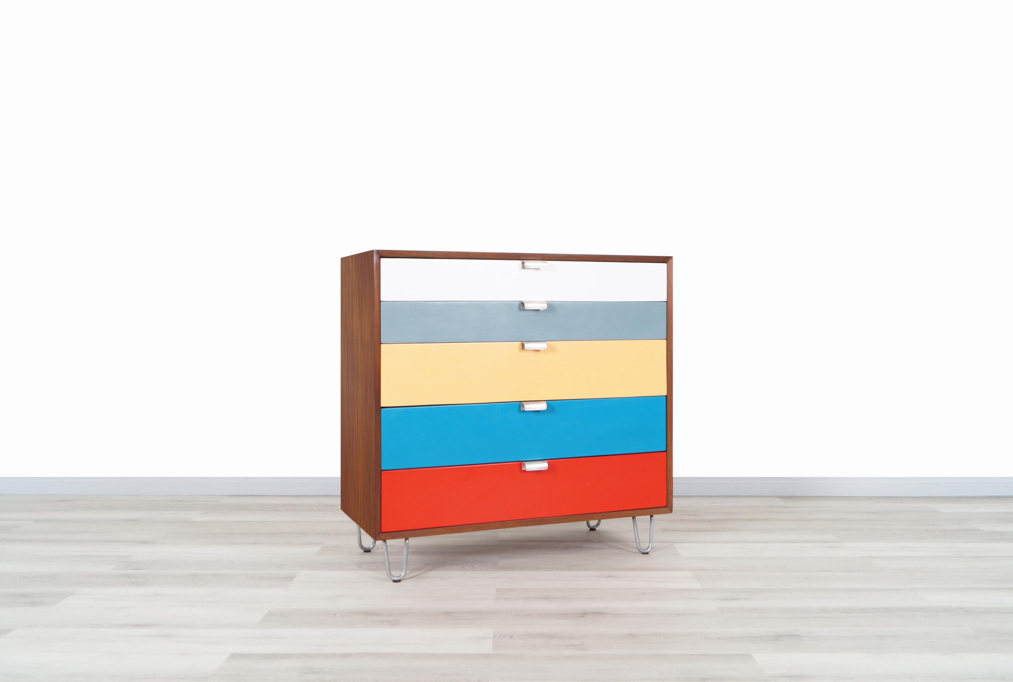 A rare vintage chest of drawers designed by iconic designer George Nelson for Herman Miller, circa 1940s. Features five multi-color dovetailed drawers, all integrated with signature sculptural steel handles. The walnut case sits on top of four