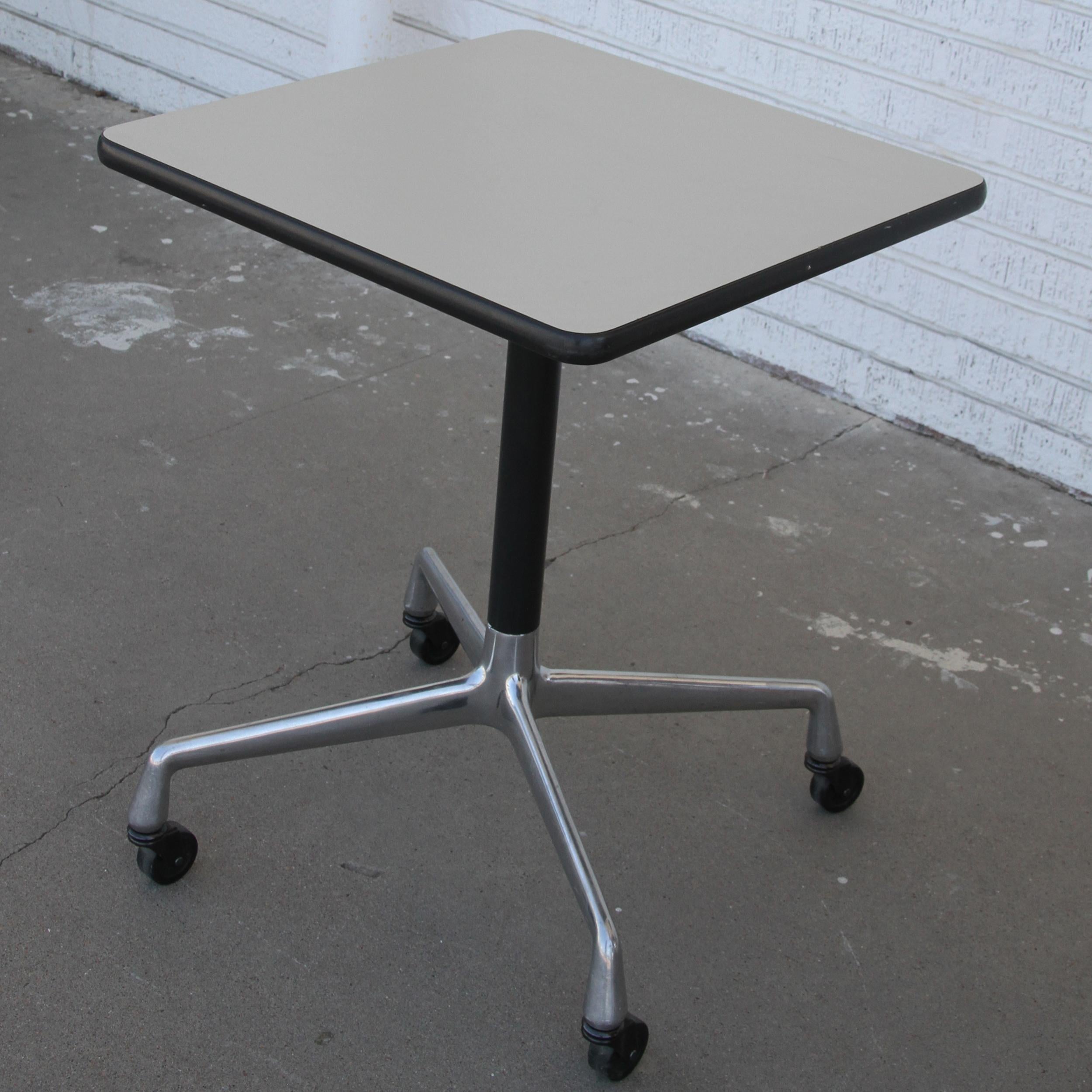 Cette table carrée Herman Miller présente des lignes gracieuses. Le socle en aluminium moulé se termine par des roulettes pour faciliter le déplacement. Le plateau en stratifié blanc permet un nettoyage facile. Il s'agit d'un complément idéal pour