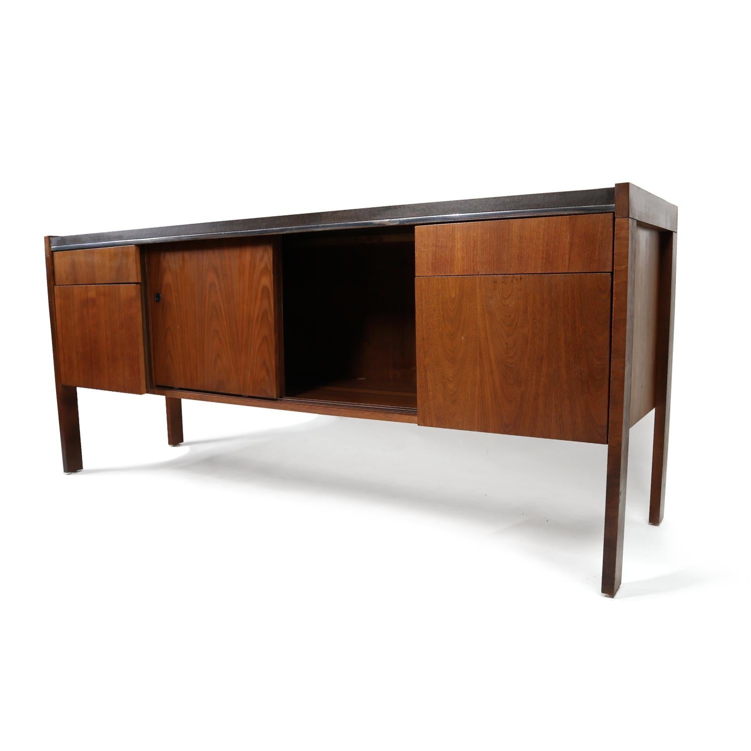Walnut office credenza by Biltrite of Canada. Fully finished backside is ideal so you don’t have to place it against a wall. The unit has two small drawers and two larger, filing drawers. Two sliding doors open to reveal an open storage area perfect