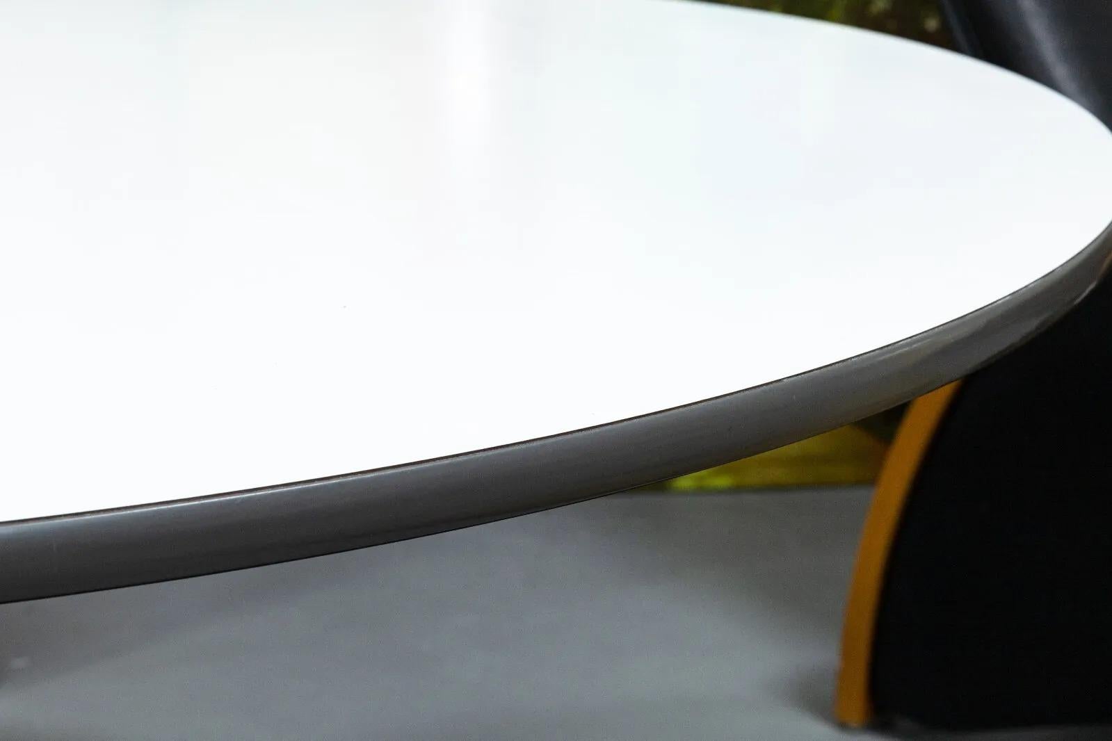 A Herman Miller dinette table. A classic, timeless design from Herman Miller. This dinette table features a wood table top with a white laminate finish, a black vinyl rim, and an aluminum x-shaped base. This table is in very good condition with some