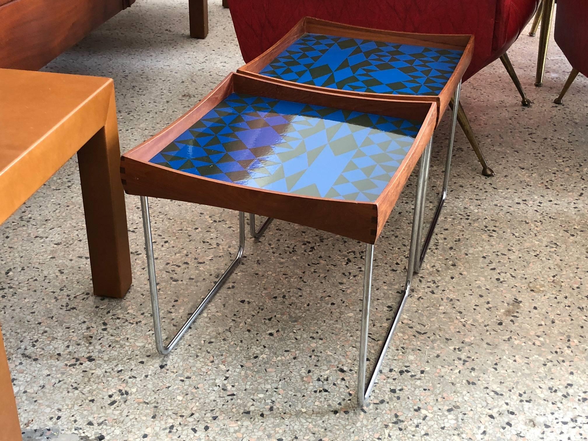 A matched pair of Norwegian enamel tray tables by Hermann Bongard for Plus, circa 1960s. Beautifully executed, removable tray tops in teak with dove tail joinery and an abstract enamel pattern. Legs collapse for easy shipping.