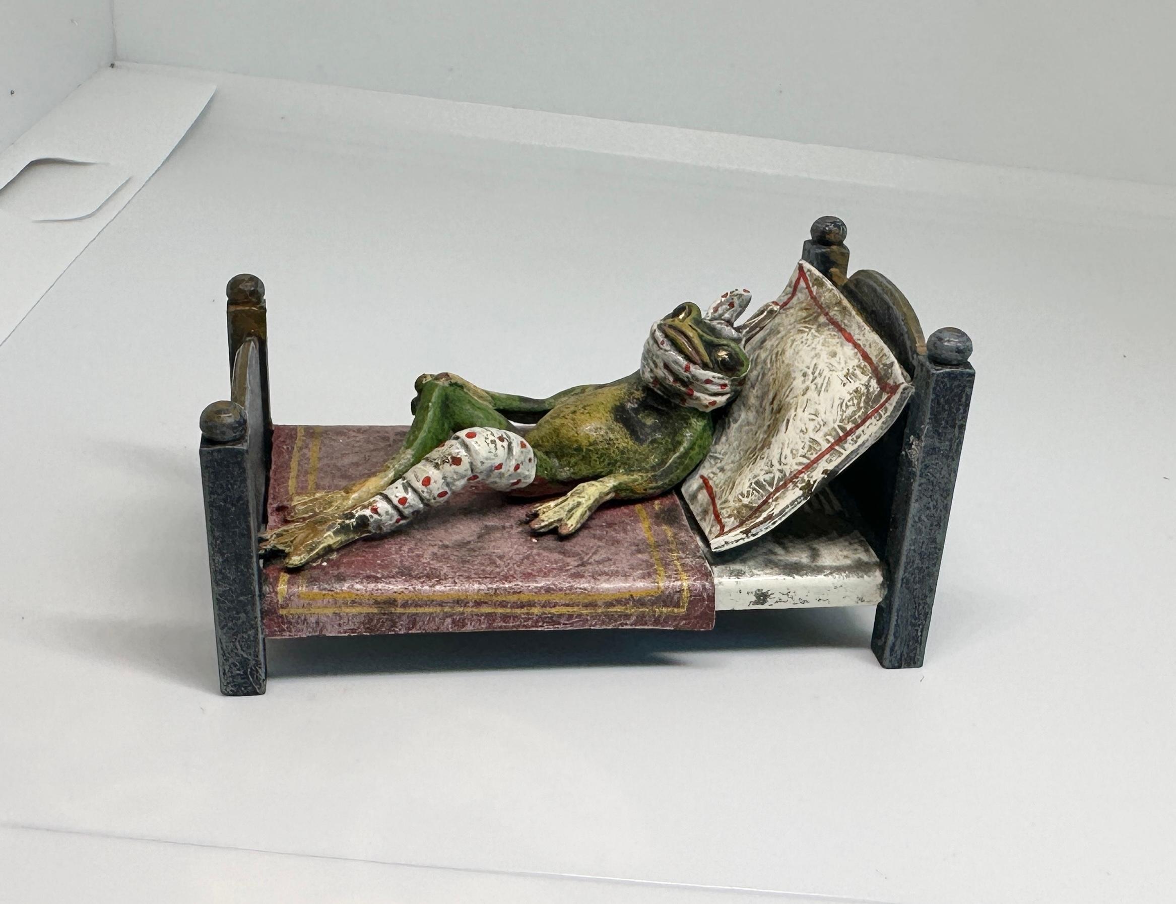 UN SUPERBO BRONZO AUSTRIACO ANTICO FIRMATO HERMANN HEUBACH GESCHUTZT AUSTRIA DI UNA RANA A LETTO CON LA TESTA E LA GAMBA FASCIATE E UN VASO DA NOTTE ACCANTO AL LETTO.  IL BRONZO RISALE ALLA FINE DEL XIX E ALL'INIZIO DEL XX SECOLO ED È UN CAPOLAVORO