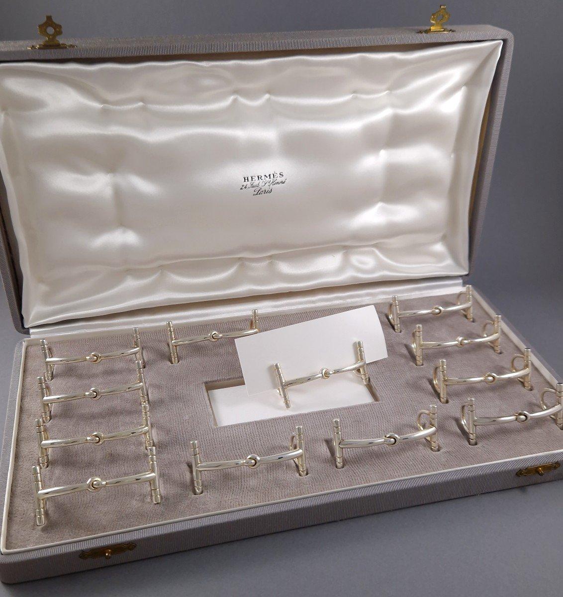 Set of 12 silver plate place card holders in the shape of a horse bit 

In its original case 
Signed Hermès Paris on each 
Length: 5.8 cm 
Height: 2.4 cm