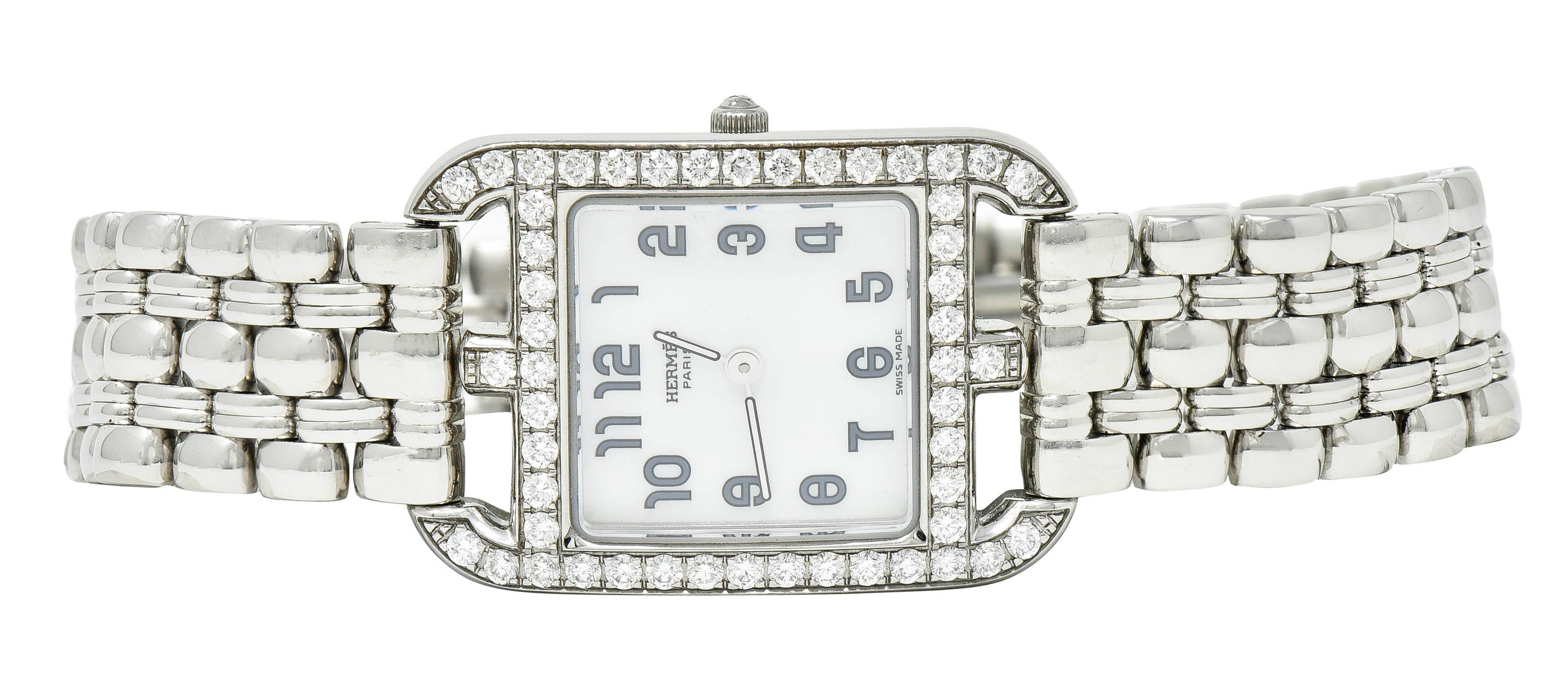 Centering a rectangular watch case designed as a buckle motif

Featuring a white mother-of-pearl watch face - covered by sapphire crystal

With stylized numerals then signed Hermēs and Swiss Made

Surrounded by round brilliant cut diamonds weighing