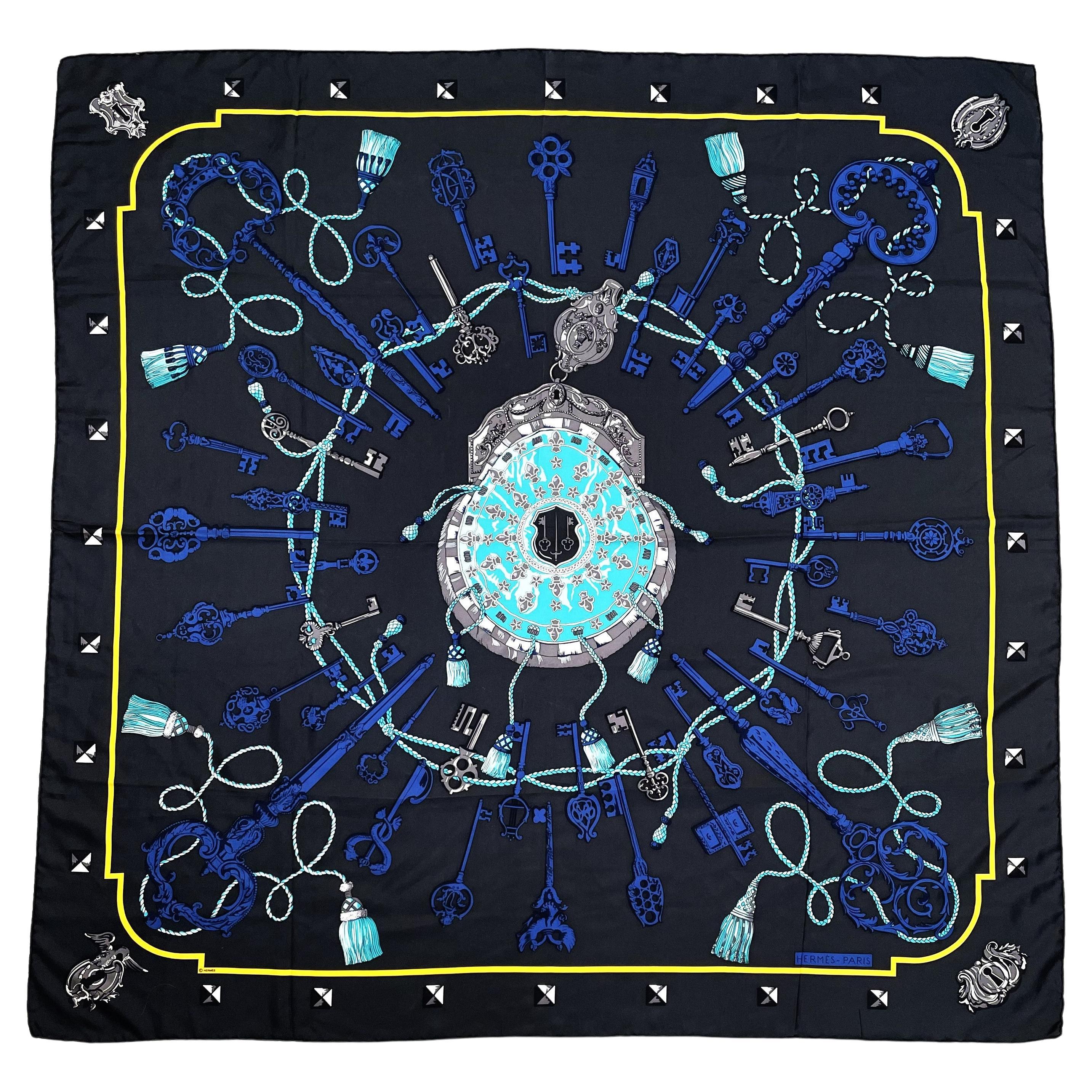 Hermes großer Schal aus 100 % Seide, 132 x 132 cm groß,  mit blauen und grauen Schlüsselmotiven, handgerollt von HERMÈS mit einem Schlüsselmotiv auf anthrazitfarbenem Hintergrund. Eine türkisfarbene Kordel mit Quaste zieht sich durch das gesamte