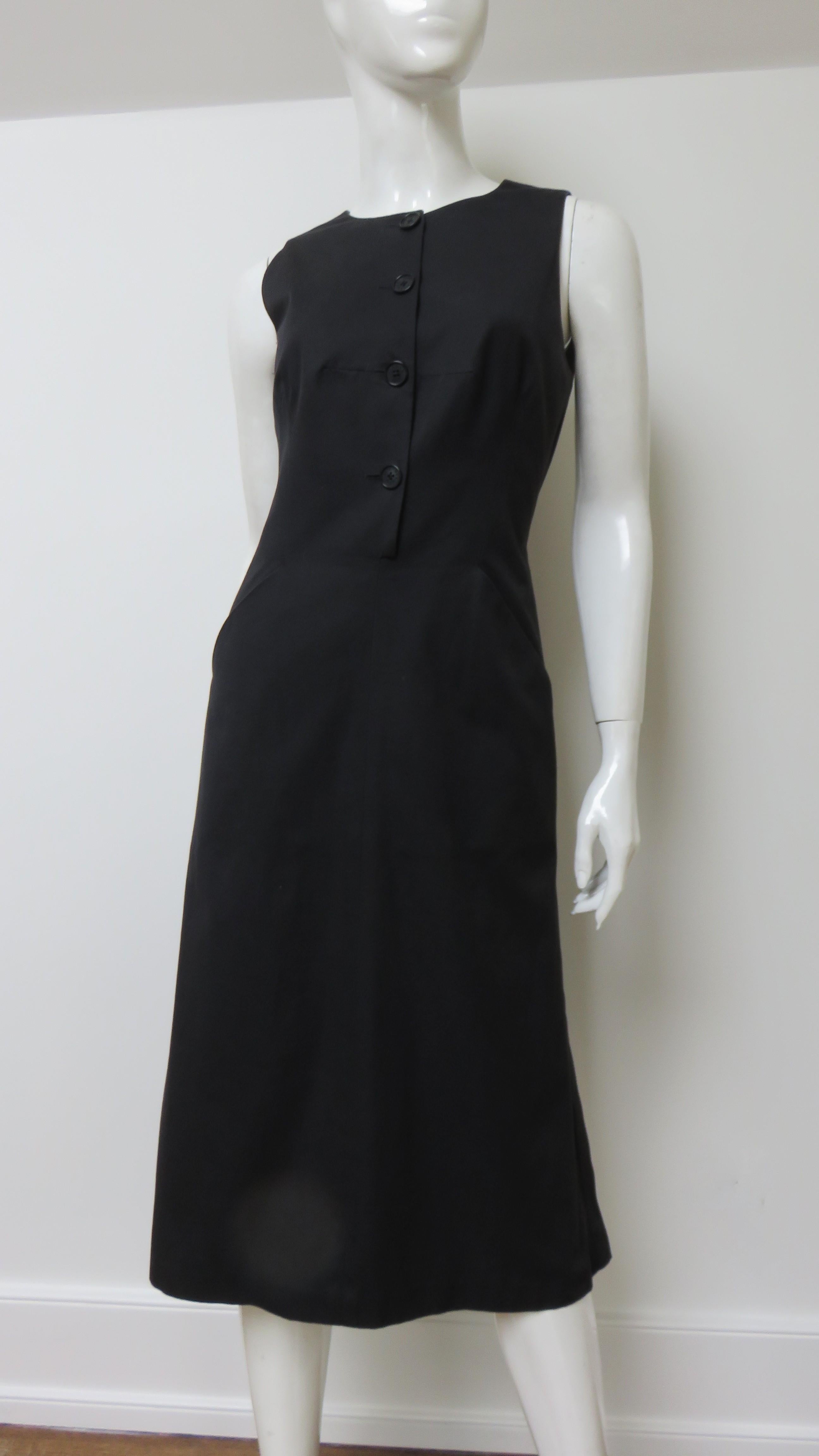 A fabulous black polished cotton dress from Hermes.  It is sleeveless with a crew neckline, button front closure to the waist, hip pockets, and a cut out back with adjustable lacing crossing it. The flare skirt has functional button closures at the