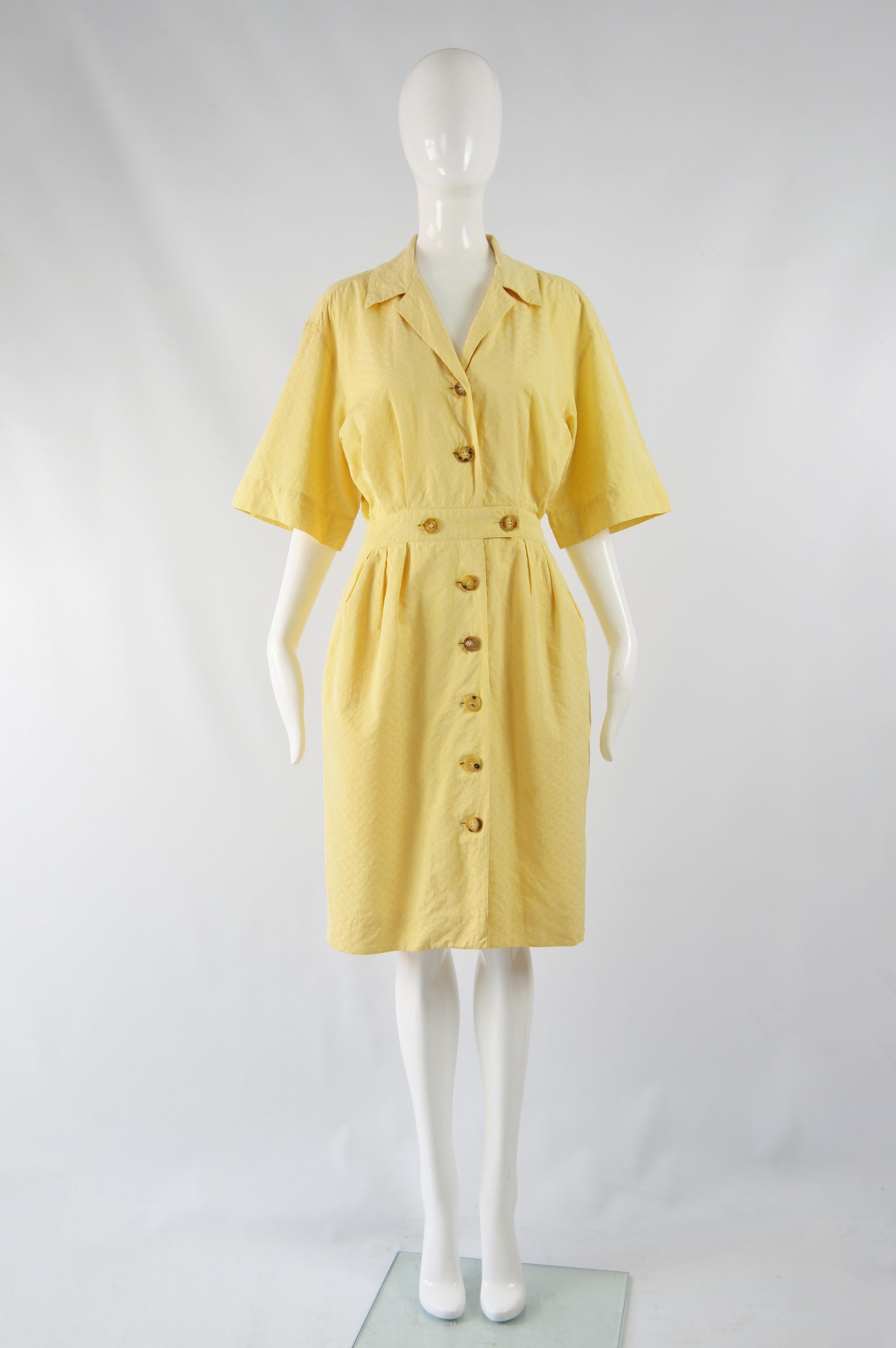 A fabulous vintage womens tea dress from the 80s by French luxury fashion house, Hermes. In a yellow textured cotton jacquard with wide, kimono inspired sleeves and a nipped waist that contrasts with the loose, blouson fit on top to create a