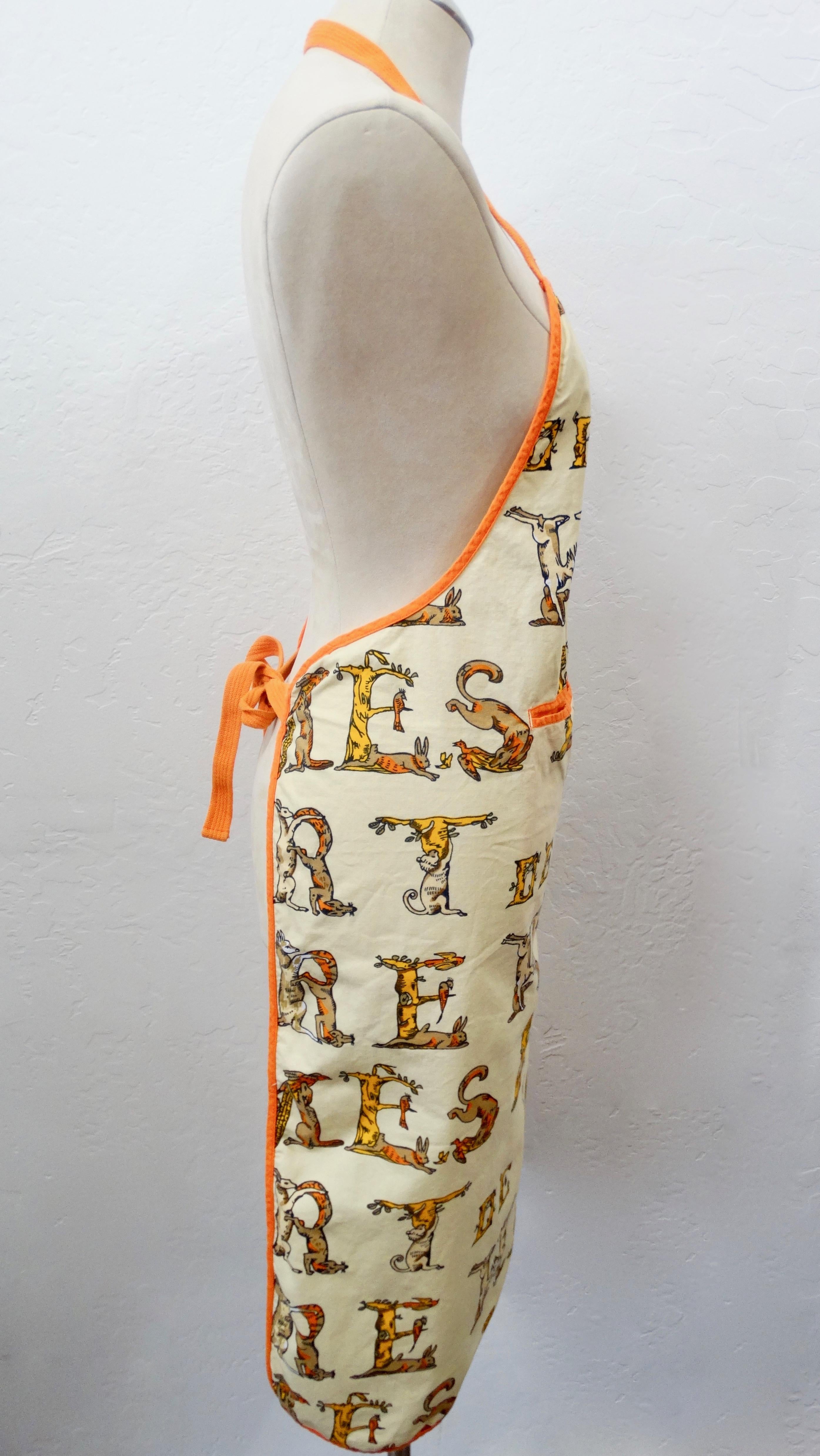 Keep yourself looking fabulous while you cook with this Hermés apron! Circa 1990s, this decorative apron is made of cotton and features various woodland creatures that are positioned to spell out 