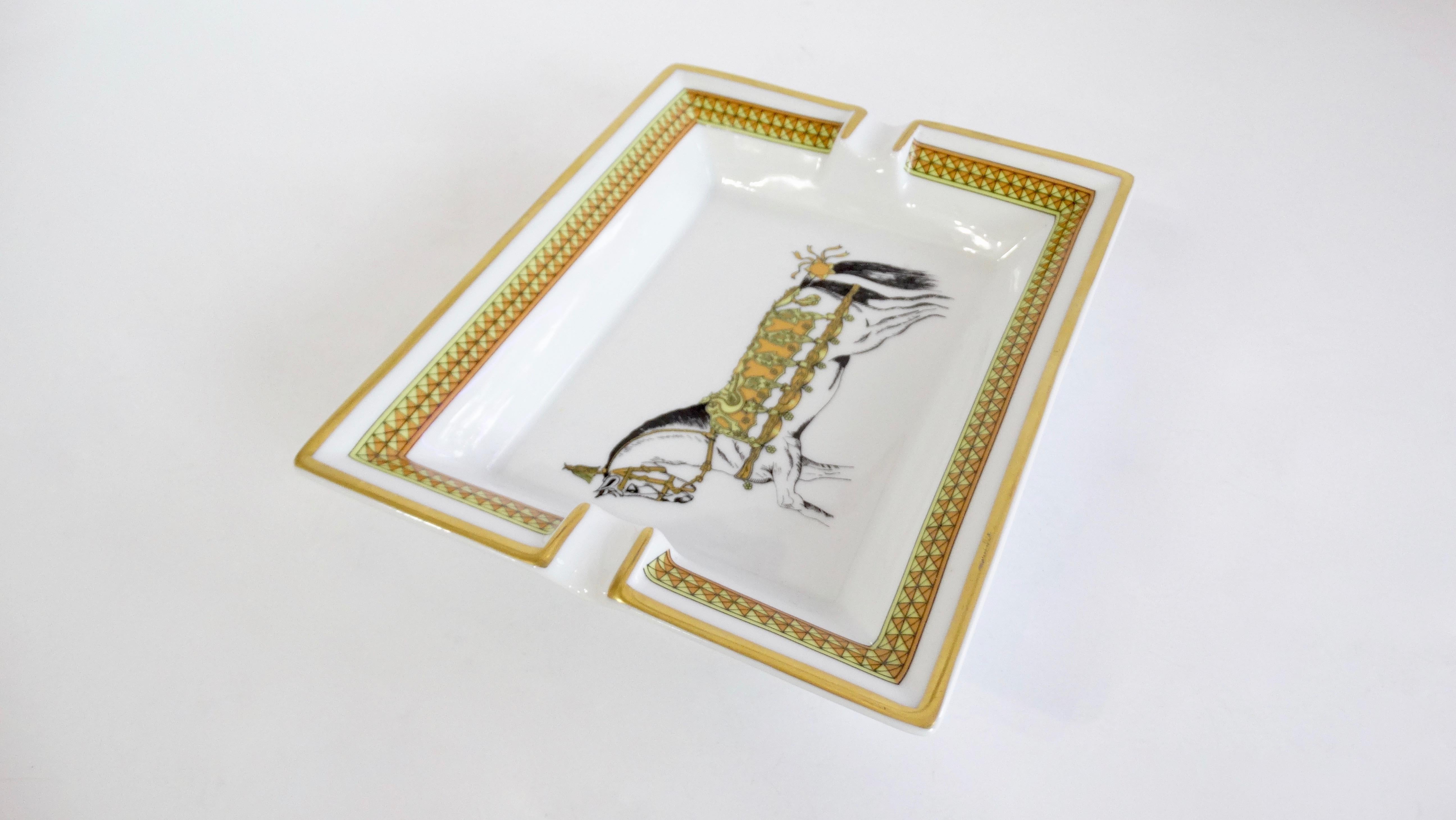 Decorate in style with this amazing Hermés tray! Circa 2000s, this tray is crafted from porcelain and features a decorated cheval horse. Trim is painted in metallic gold and includes a decorative pattern framing the inside. Use to elevate your cigar