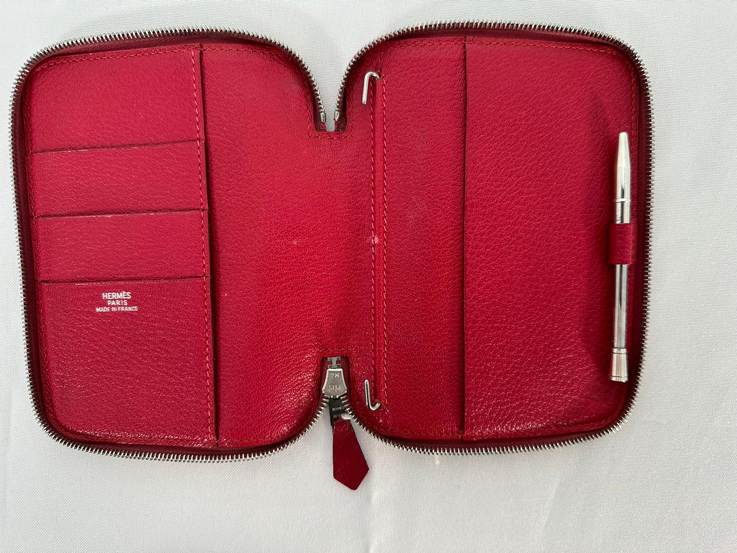 Hermes vintage zip around Globe Trotter PM Agenda Cover/Wallet with Sterling silver Pen from 2002. Clemence leather in a slightly pinkish red. The wallet/agenda opens with a silver zipper on 3 sides, beginning & ending 1