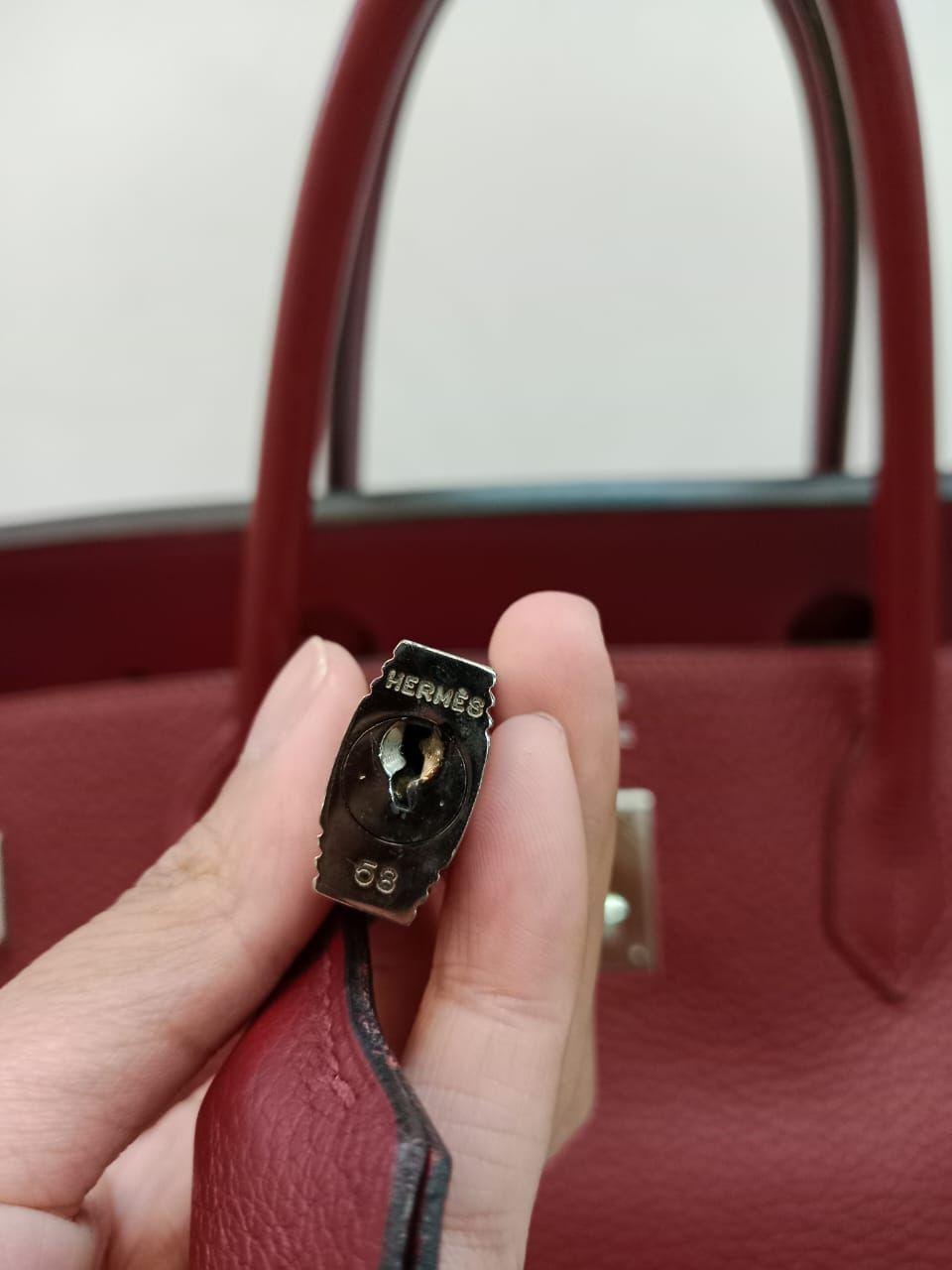 Magnifique Birkin 40 vintage en rubis avec quincaillerie en palladium. L'ensemble est en très bon état, avec un léger ternissement de la quincaillerie. Légers plis et éraflures sur le corps en cuir. Stamp Square H (2004). Il est livré avec son sac à