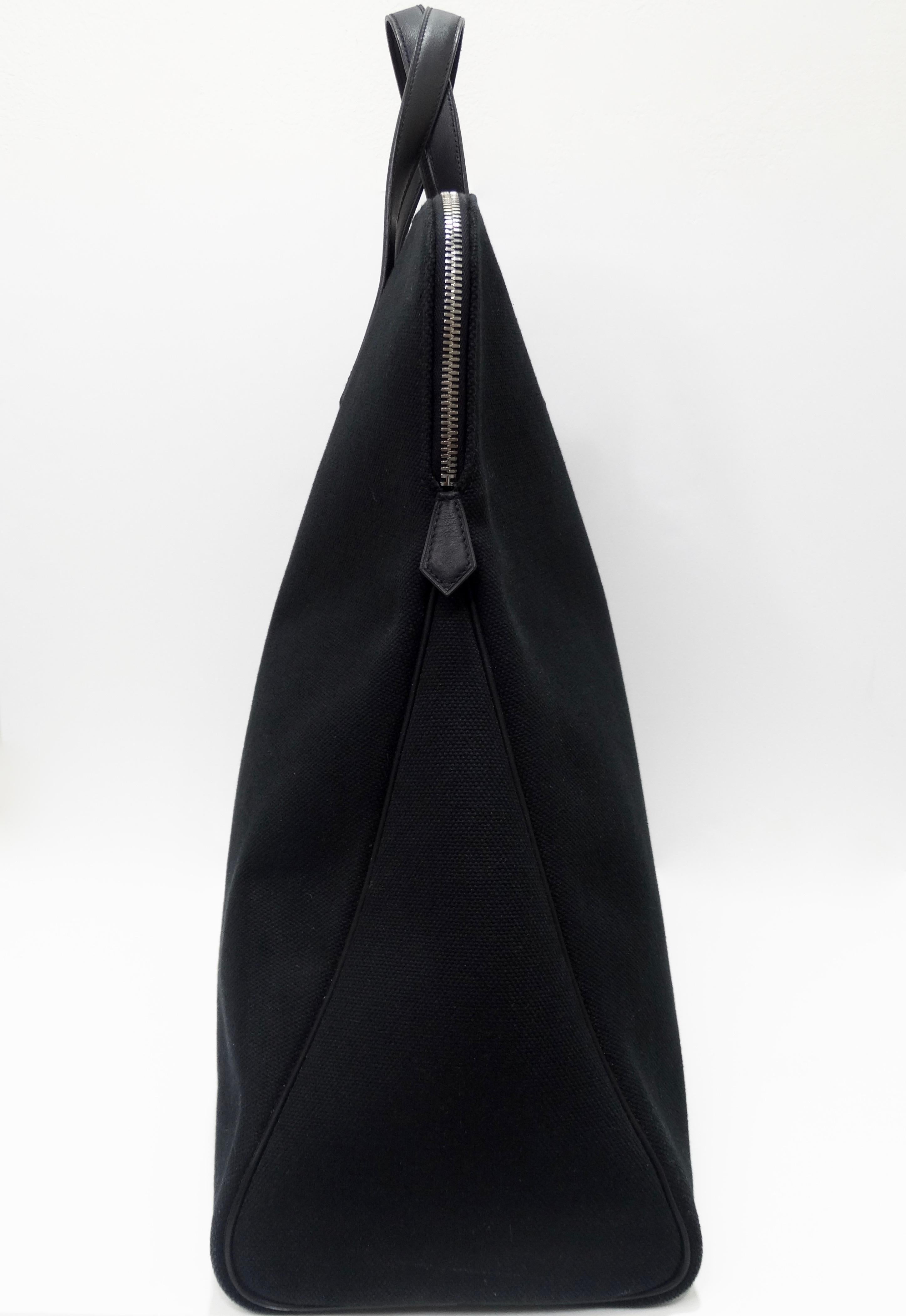 Hello Hermés lovers! Circa 2006, this large travel tote is crafted from black canvas and features pristine black stitching, dual black leather top handles with circle cutouts, black leather pipping, silver tone hardware and a top zipper closure with