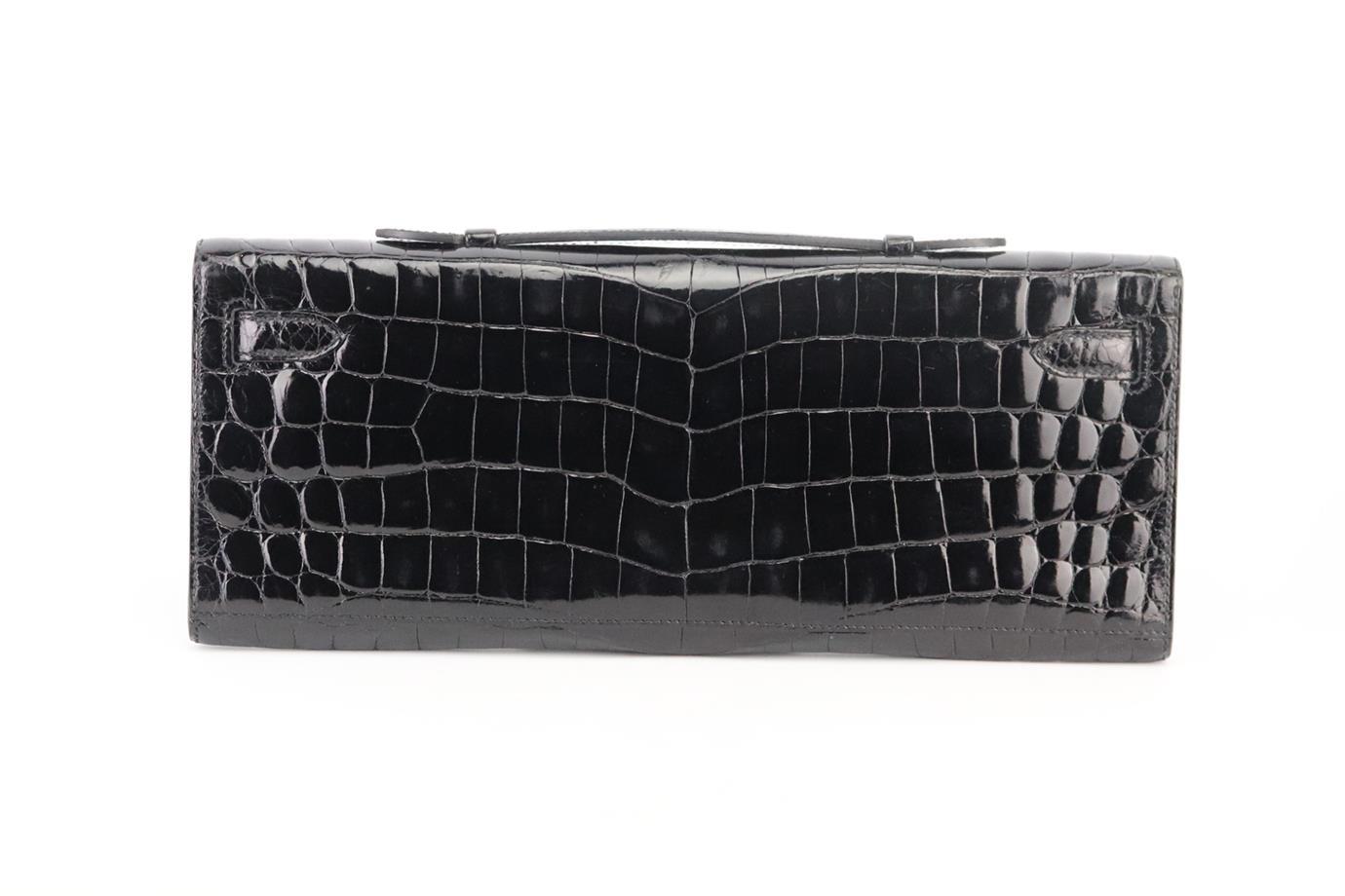 Hermès 2011 Kelly Cut Niloticus Crocodile Clutch. Made in France, this beautiful 2011 Hermès ‘Kelly Cut’ clutch bag has been made from black ‘Niloticus’ crocodile exterior in ‘Noir’ with matching leather interior, this piece is decorated with