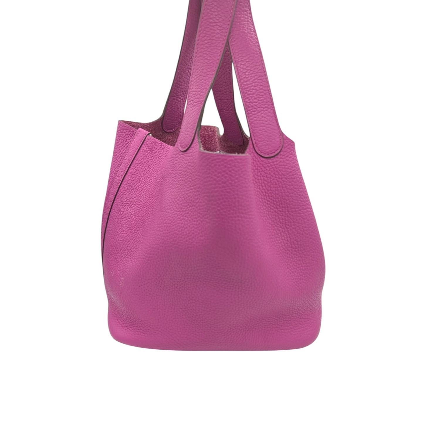Hermès Clemence Picotin Lock 18 PM in Magnolia. This chic tote is crafted of soft Taurillon Clemence calfskin leather in pink. This unique tote is a one piece handbag with top handles that extend from the sides with an extra layer of leather for