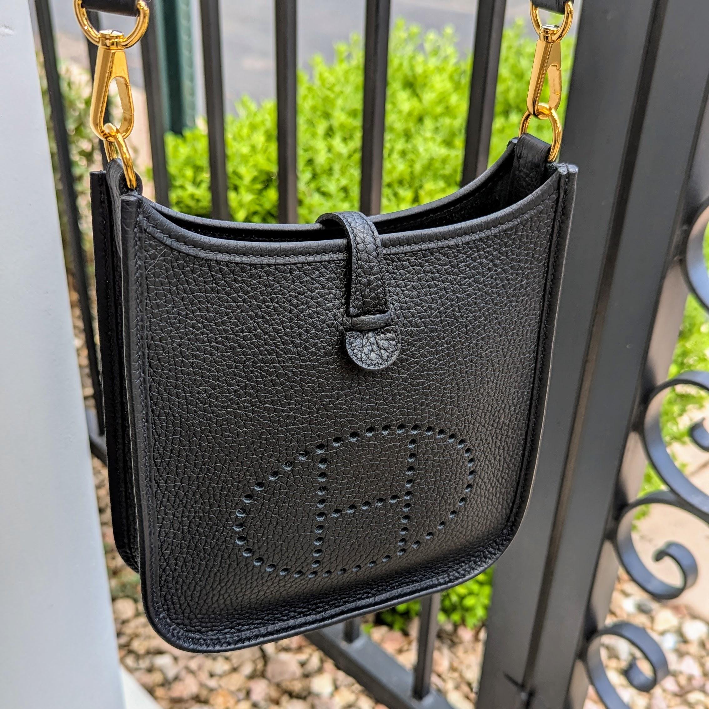 From the 2022 Collection. This petite crossbody messenger bag is finely crafted of rich Taurillon Clemence calfskin leather in Black. The bag features a canvas body strap, polished gold hardware, and a perforated Hermes H inside an oval on the front