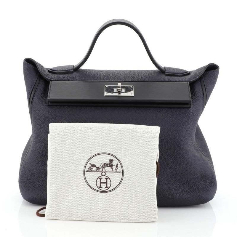 This Hermes 24/24 Handbag Togo with Swift 35, crafted in Bleu Nuit blue Togo and Noir black Swift leather, features a leather top handle, exterior back slip pocket and palladium hardware. Its turn-lock closure opens to a Bleu Nuit blue Swift leather