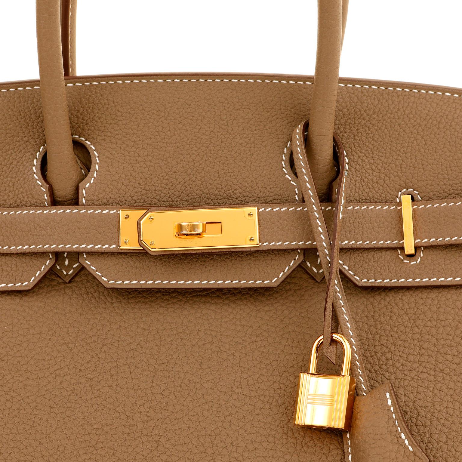 This authentic Hermès 30 cm Taupe Togo Birkin is in pristine unworn condition; never carried.   Hand stitched by skilled craftsmen, wait lists of a year or more are common for the Hermès Birkin. Neutral greige taupe Togo is uniquely accented with