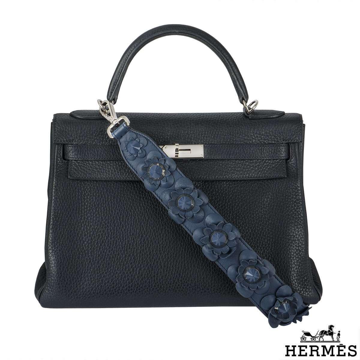 An exquisite Hermès 35cm Kelly bag. The navy blue clemence leather bag is detailed with palladium hardware. The bag has a single rolled top handle, complete with padlock and a hanging clochette and keys. The interior features one zipped and two open