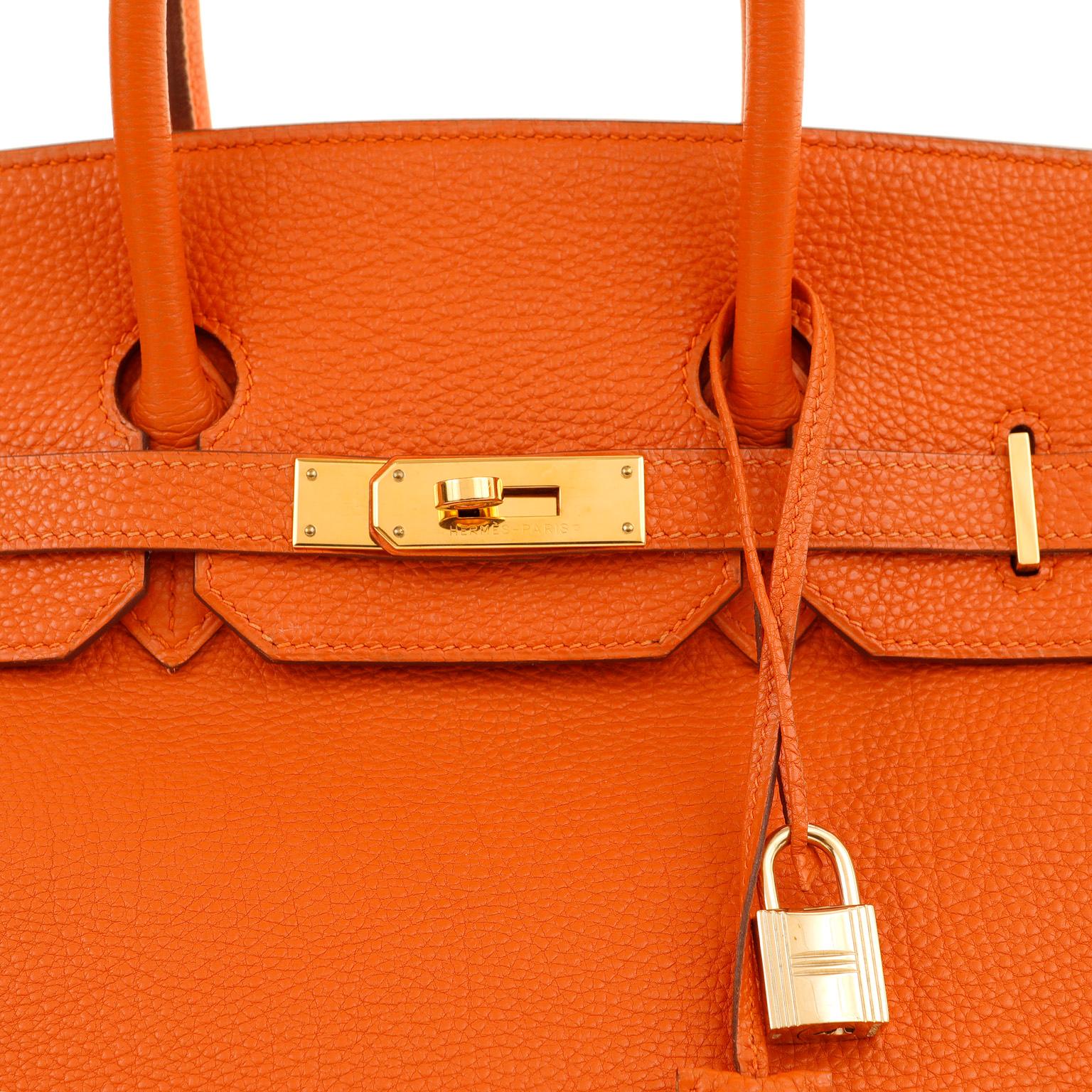 This authentic Hermès 35 cm Orange Togo Birkin is in excellent condition.  Hand stitched by skilled craftsmen, wait lists of a year or more are common for the Hermès Birkin. Iconic Orange paired with gold hardware is a brilliant pop color for any