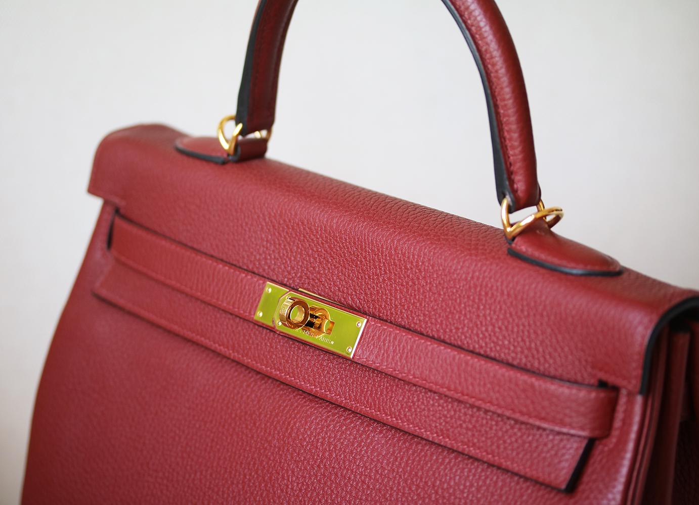 This extremely beautiful Hermès Kelly Retourne 35 Clemence Bag in Rouge Grenat with Gold Hardware is a must have for your collection! The beautiful rich burgundy-tone exterior of the bag works well with every outfit. Tonal stitching. The bag is