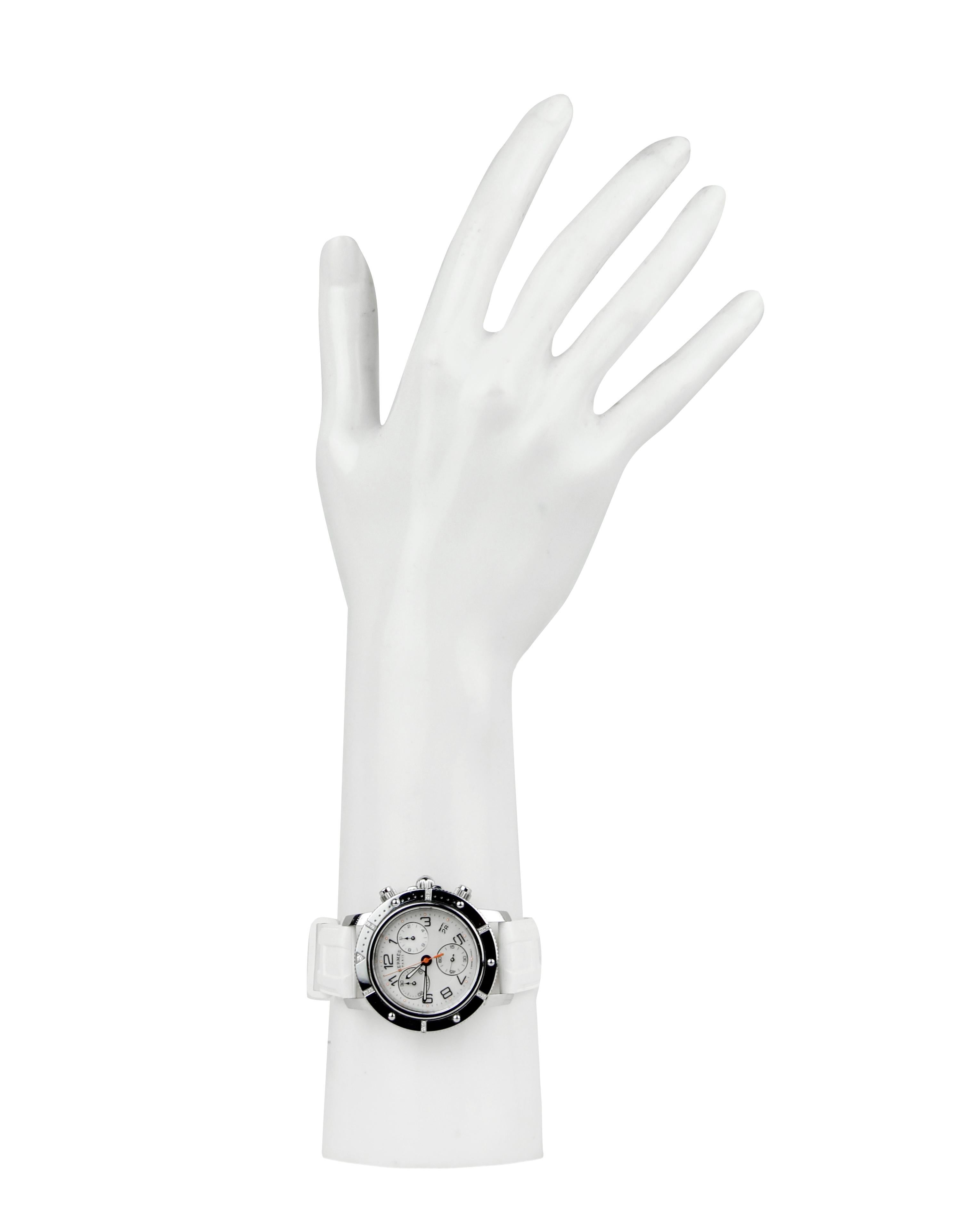 Hermes Cronograph Quartz Clipper Watch w/ Diamonds & White Rubber Band. Cadran en nacre avec index en chiffres arabes

Fabriqué en : Suisse
Couleur : argent, blanc
MATERIAL : Acier inoxydable, caoutchouc, diamants, nacre.
Fermeture/ouverture :