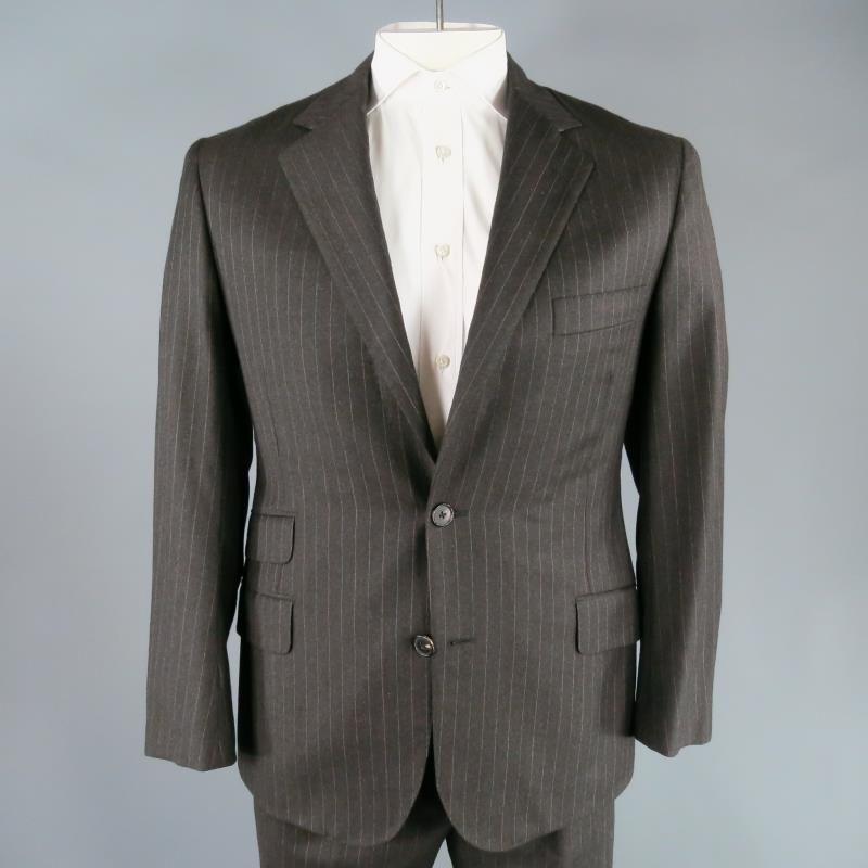 HERMES suit comes in a dark charcoal with alternating red and blue pinstripe detail.  This updated take on a timeless look comes in a medium gauge, dark charcoal wool fabric. The jacket is single breasted with a notch lapel, single vented in the
