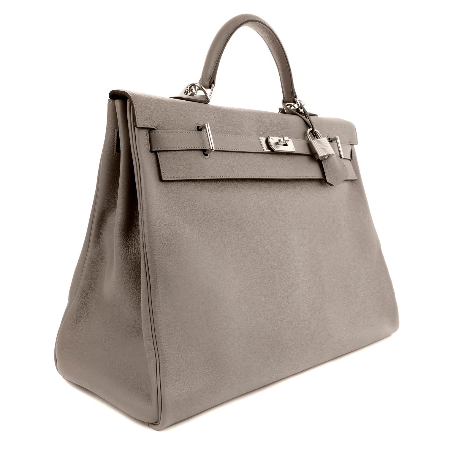 This authentic Hermès 50 cm Grey Evercolor Voyage Kelly is in pristine condition with the protective plastic intact on the hardware.   Hermès bags are considered the ultimate luxury item worldwide.  Each piece is handcrafted with waitlists that can
