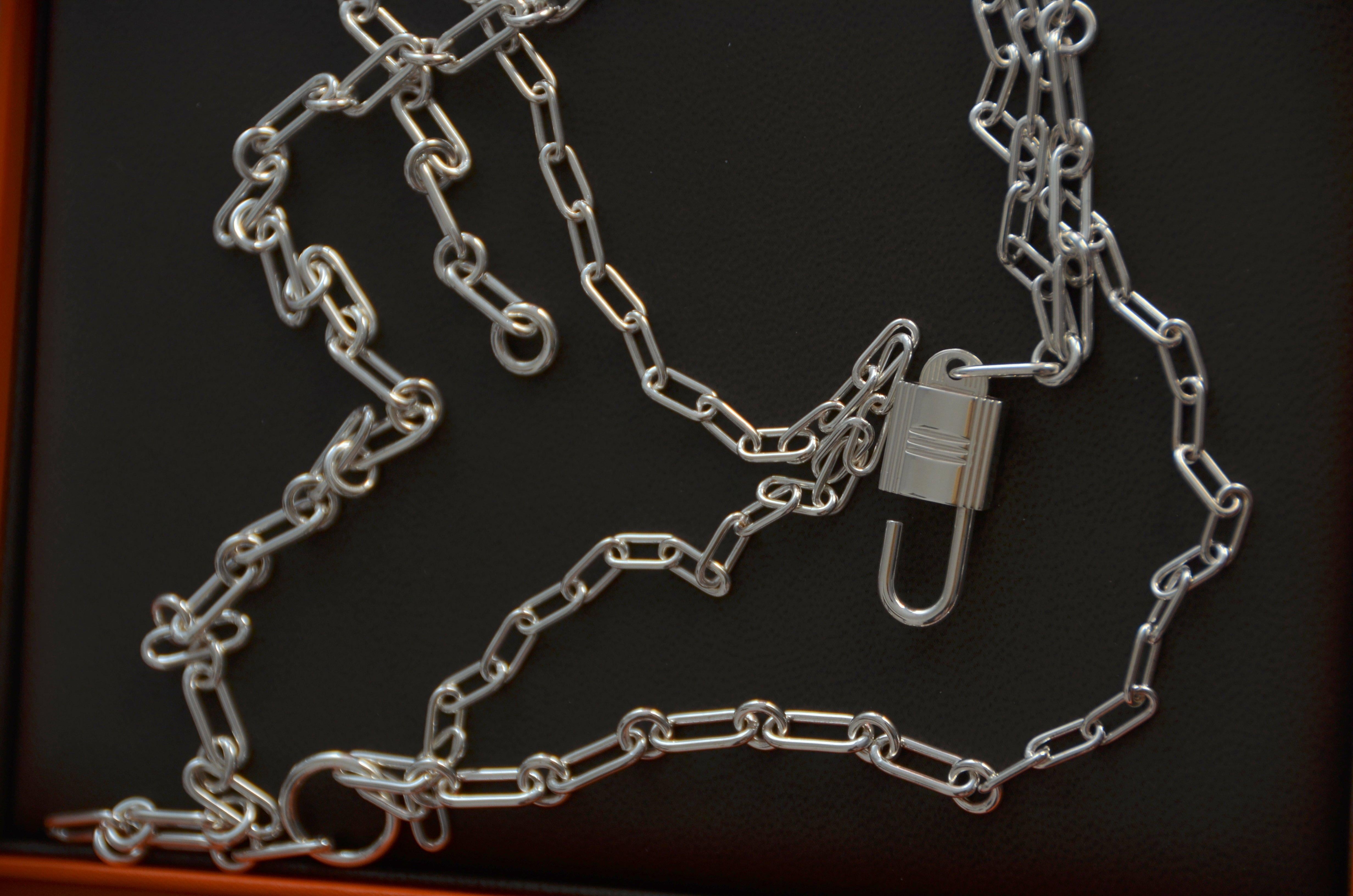 Hermes Alphakelly lange Halskette, mittleres Modell
Lange Halskette aus Sterlingsilber. Das Vorhängeschloss, ein ikonisches Motiv der Kelly-Bag, erscheint in einer silbernen Version und zeigt ein Zusammenspiel von unterschiedlich großen
