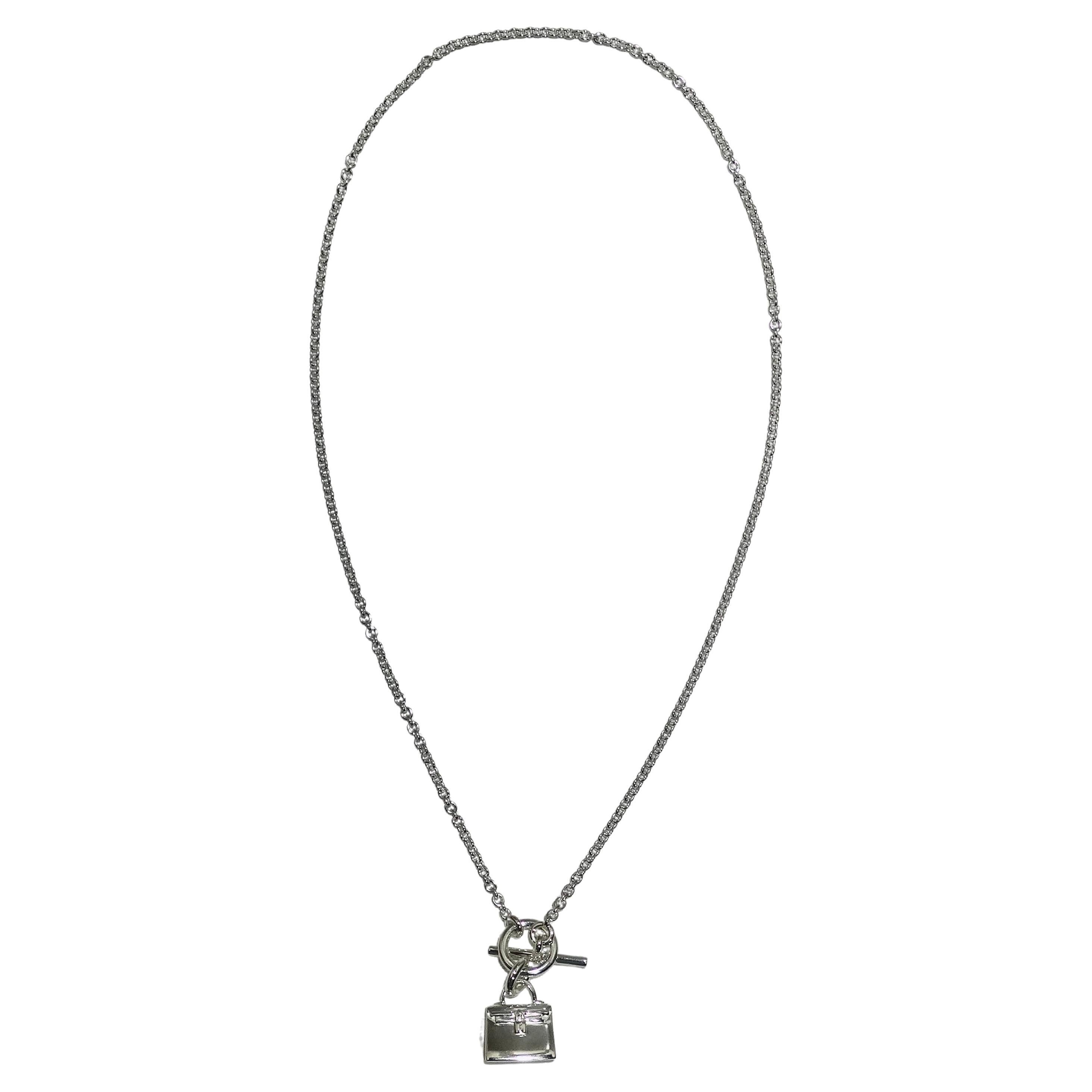 Introducing the Hermes Amulet 925 Silver Kelly Pendant Necklace, a delicate and subtle piece that captures the essence of Hermes' iconic design. This beautiful necklace features a sterling silver chain with a toggle closure, offering a secure and