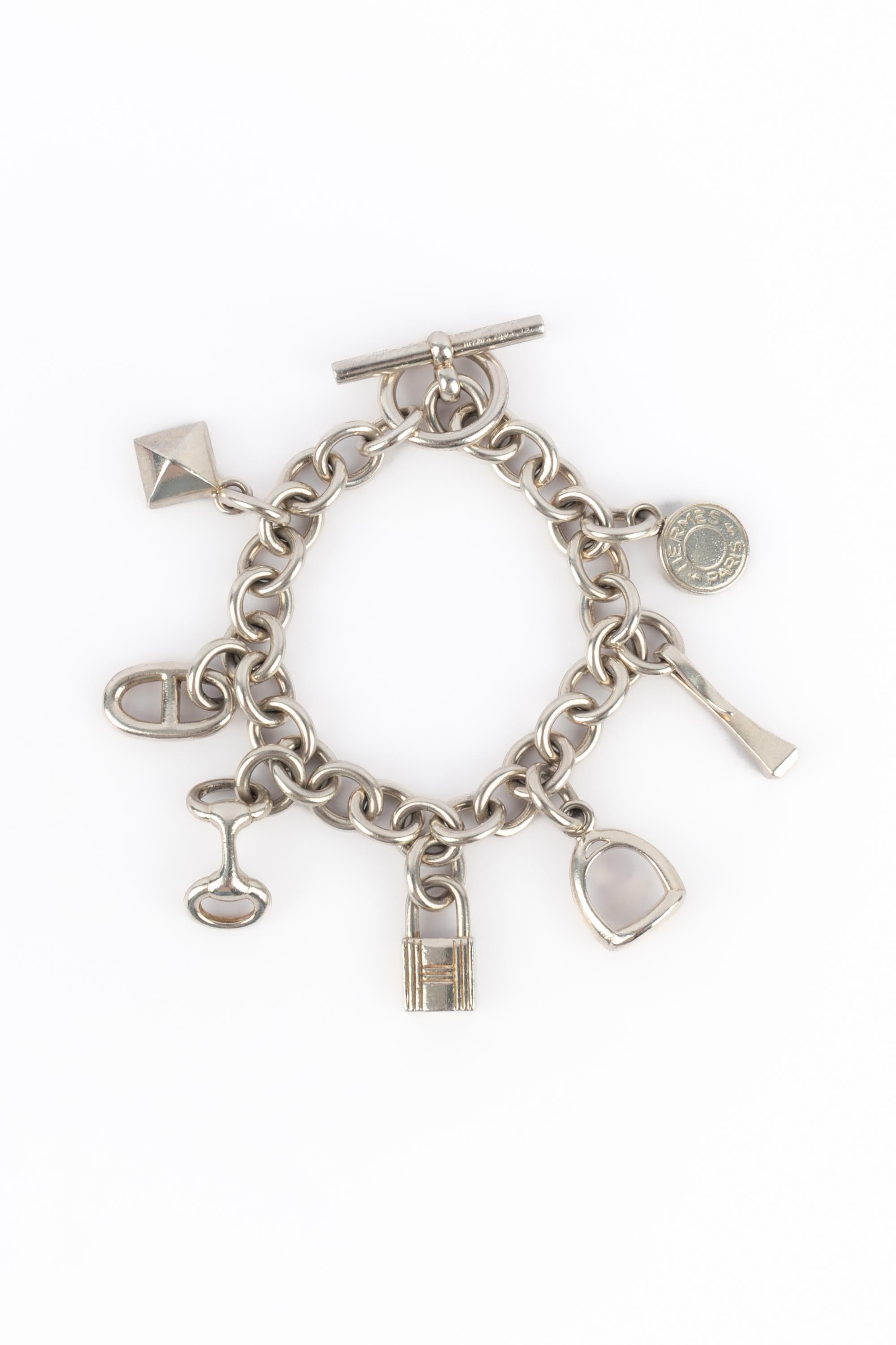 HERMÈS - 925 Sterling silver bracelet with 7 charms representing the House of Hermès' symbols; saddle stud, nausicaa, anchor chain, Medor, padlock, stirrup.

Condition:
Very good condition

Dimensions:
Length: 19 cm

SKU:BRA107