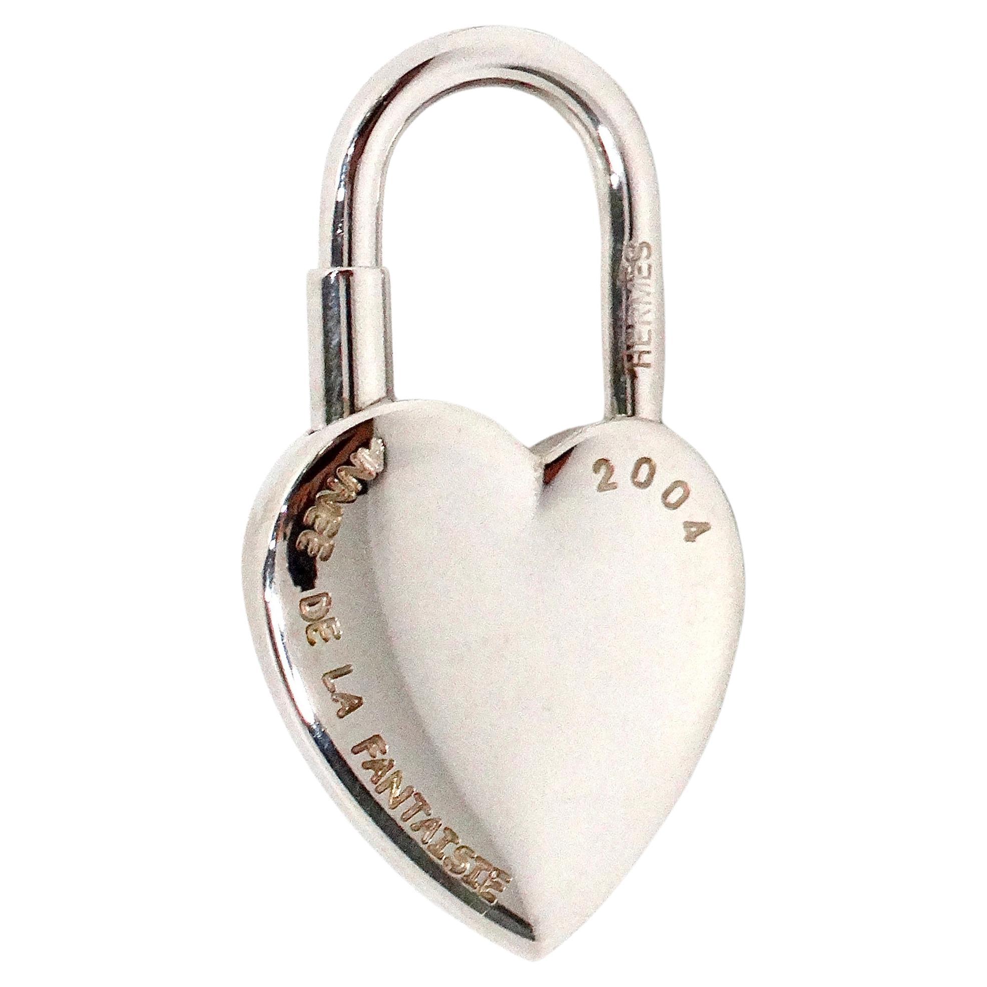 The Hermes Annee De La Fantasie Palladium Plated Heart & Key Padlock Charm from 2004 is a captivating piece that embodies the elegance and craftsmanship synonymous with the Hermes brand. Crafted with palladium plating, this charm features a delicate