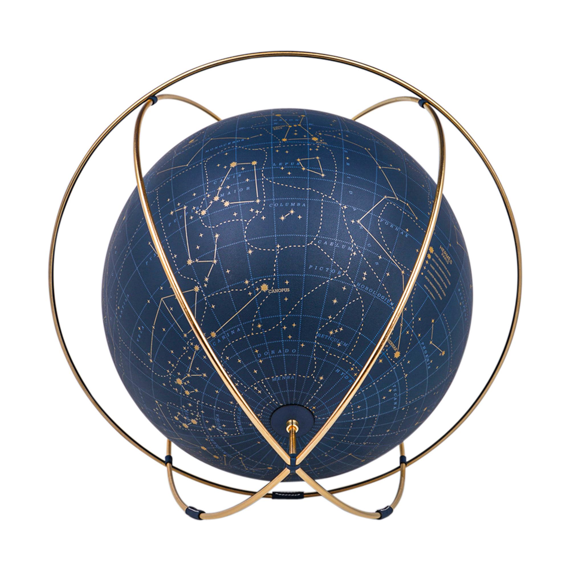 Mightychic bietet einen Hermes Apollo 24 Himmelsglobus in der Farbe Blue de Prusse an.
Die aus 12 ummantelten Stücken bedruckten Leders gefertigten Intarsien sind exquisit.
Der Globus schwebt auf den Ringen und schafft eine wunderschöne freie Form,