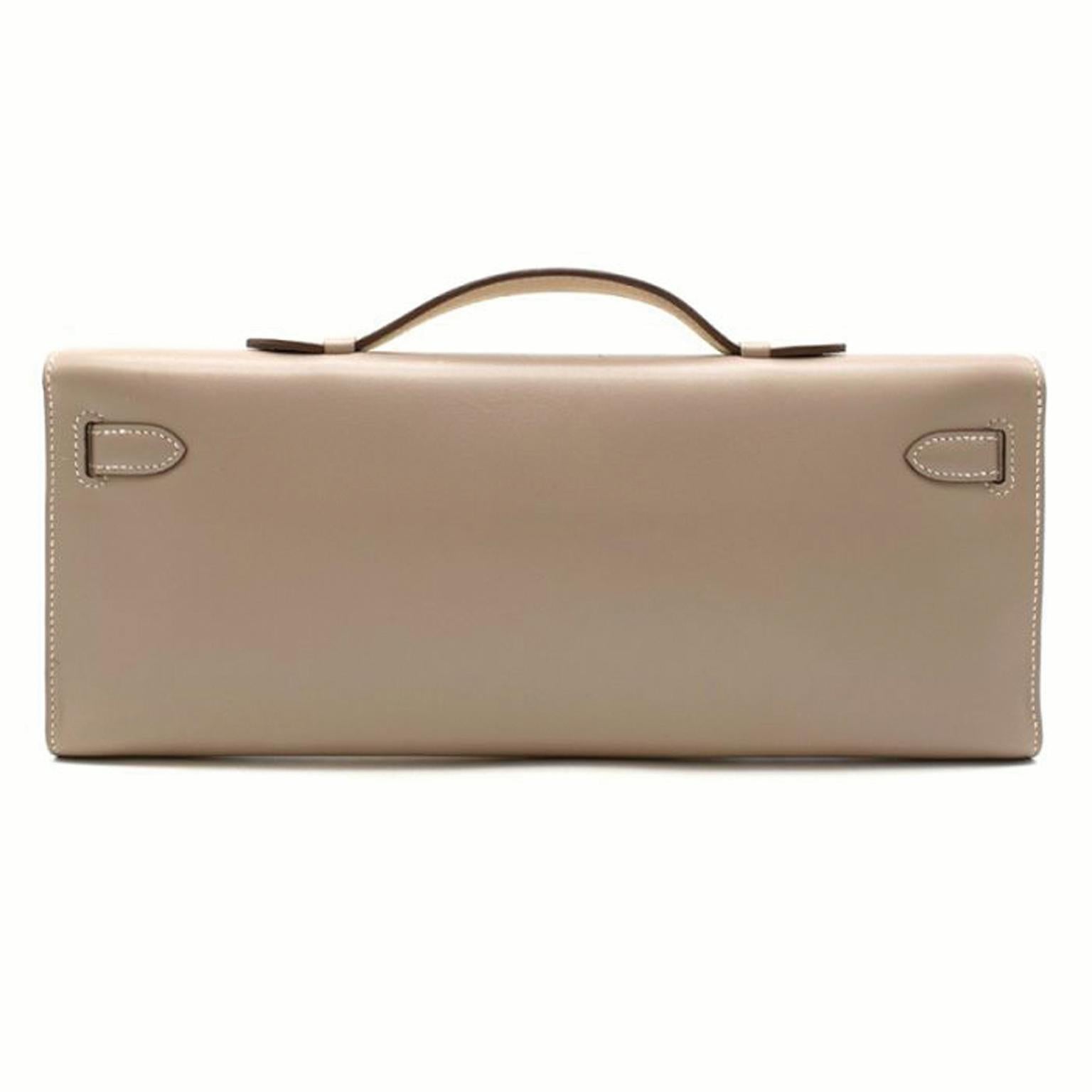 Crafted in France from supple swift leather, this exotic Agile Kelly Cut Clutch Bag by Hermès features tonal stitching, front straps and a top flat handle. The toggle closure is accented by silver-tone Guilloche palladium hardware and opens to
