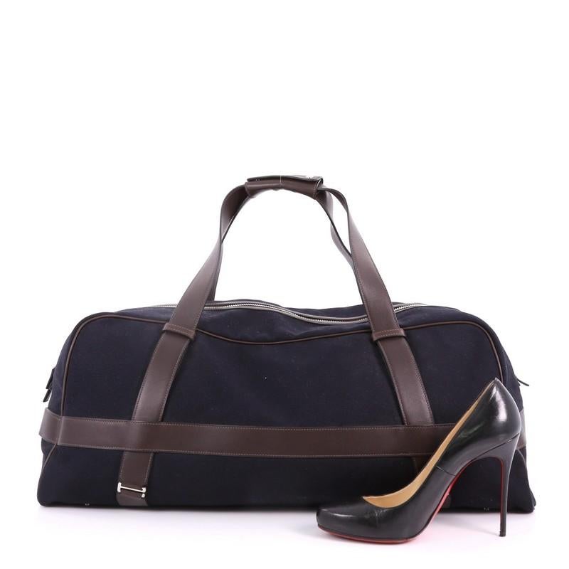 This Hermes Arion Duffle Bag Canvas with Leather, crafted from blue marine toile canvas and brown ebene leather, features dual leather handles, and palladium-tone hardware. Its zip closure opens to a brown fabric interior with slip pocket. Date