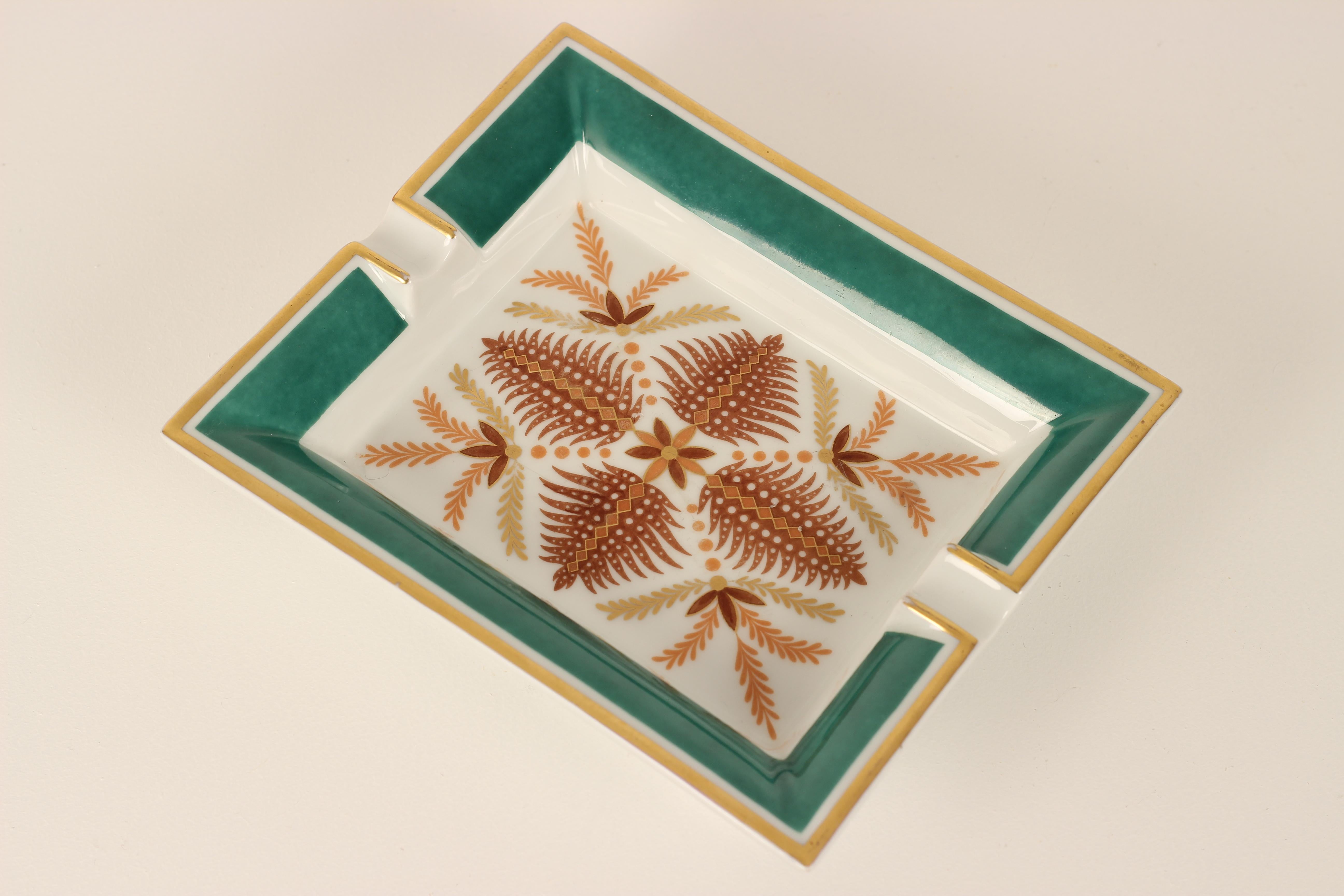 Hermes ashtray or vide-poche Catchall in the botanical style, featuring stylised depiction of ferns and leaves in outline form. With a gilt edge and gem coloured green border. In good overall condition with some minor blemishes (no chips or cracks)