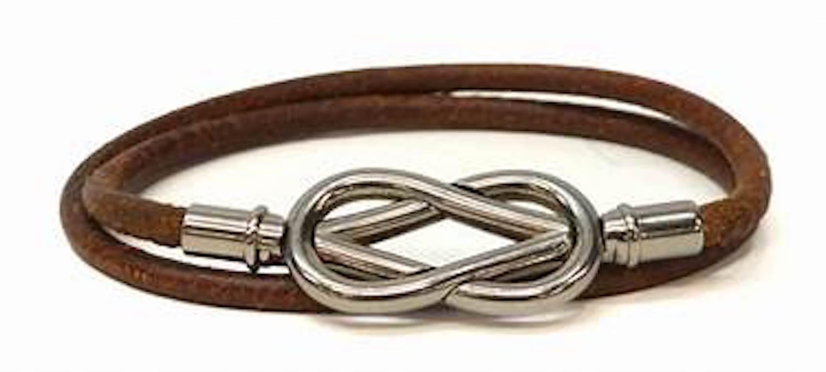 Hermes cognac color leather round cord with rhodium plate square knot clasp. Knot is 1.38 inches wide and .75 of an inch high not including the rhodium end pieces that hold the leather cord ends. With the rhodium end pieces the clasp is 2 inches