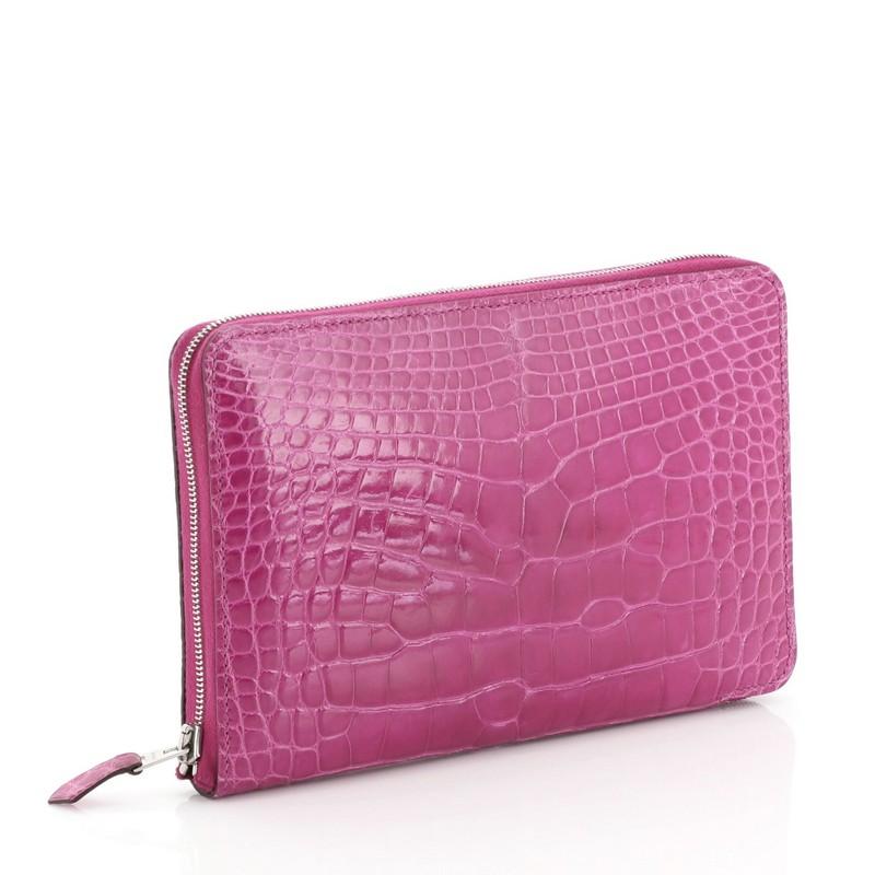 This Hermes Azap Combined Wallet Alligator GM, crafted from genuine Rose Scheherazade pink Shiny Alligator, features palladium hardware. Its zip around closure opens to a Rose Scheherazade pink Chevre leather interior with multiple card slots, slip