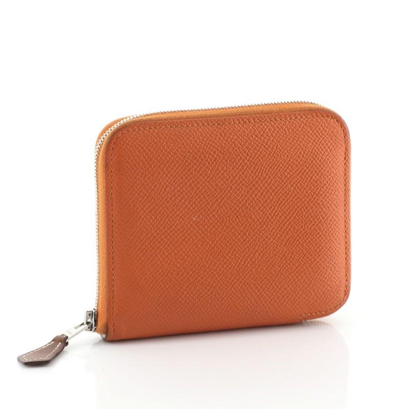 This Hermes Azap Zip Around Wallet Silk'in Epsom Compact, crafted from Orange H orange Epsom leather, features palladium hardware. Its zip around closure opens to a Multicolor Silk interior with slip pockets and a center zip pocket. Date stamp