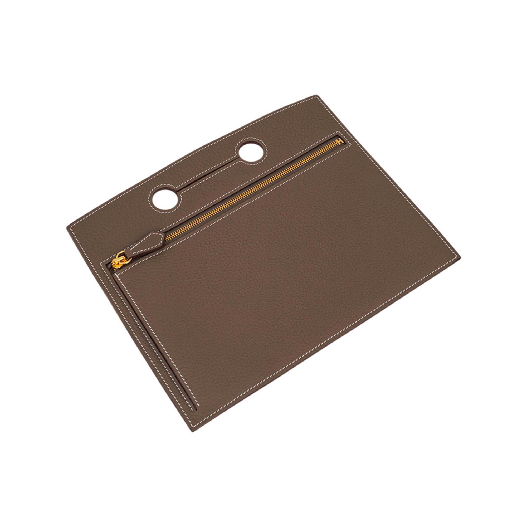 Mightychic offers an Hermes Backpocket 25 Pouch featured in neutral Etoupe.
Beautiful in Togo leather with gold zipper.
This flat Backpocket fits easily over the handle and features a partitioned interior.
In a fabulous neutral color!  And fun to