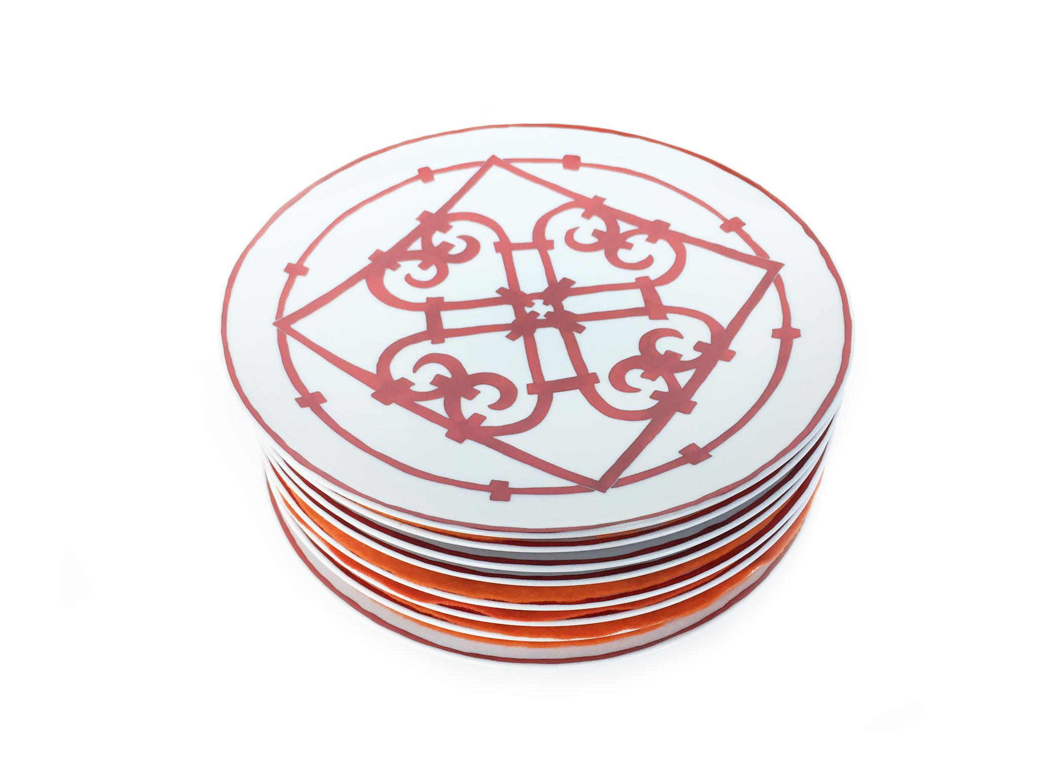 This set of Hermès porcelain china consists of 8 American dinner plates, 8 dessert plates, and 8 bread and butter plates. Their bold latticework design is hand-painted in a rich cardinal red, inspired by Andalusian ironwork. The Hermès signature is