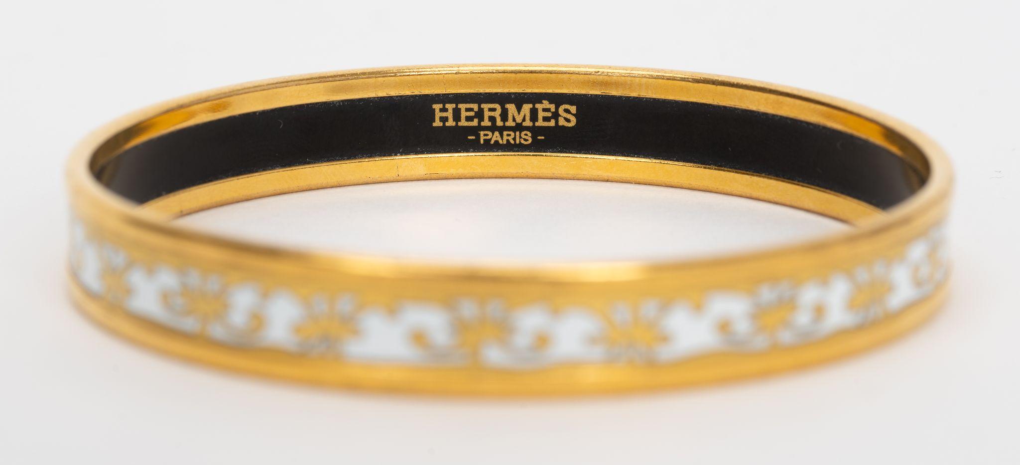 Bracelet Hermes Balcons Du Guadalquivir. Le bracelet Hermès en émail imprimé avec quincaillerie plaquée or sur fond blanc. Taille 62. Le bracelet est parfait pour être empilé. Livré avec une pochette en velours.
