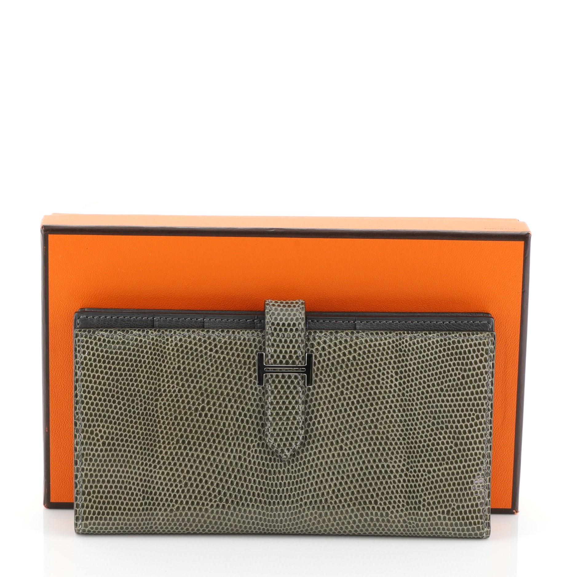 This Hermes Bearn Wallet Lizard Long, crafted from genuine Gris Fonce gray Niloticus Lizard, features a plated 'H' tab closure and palladium hardware. Its tab closure opens to a Gris Fonce gray Chevre leather interior with multiple card slots and