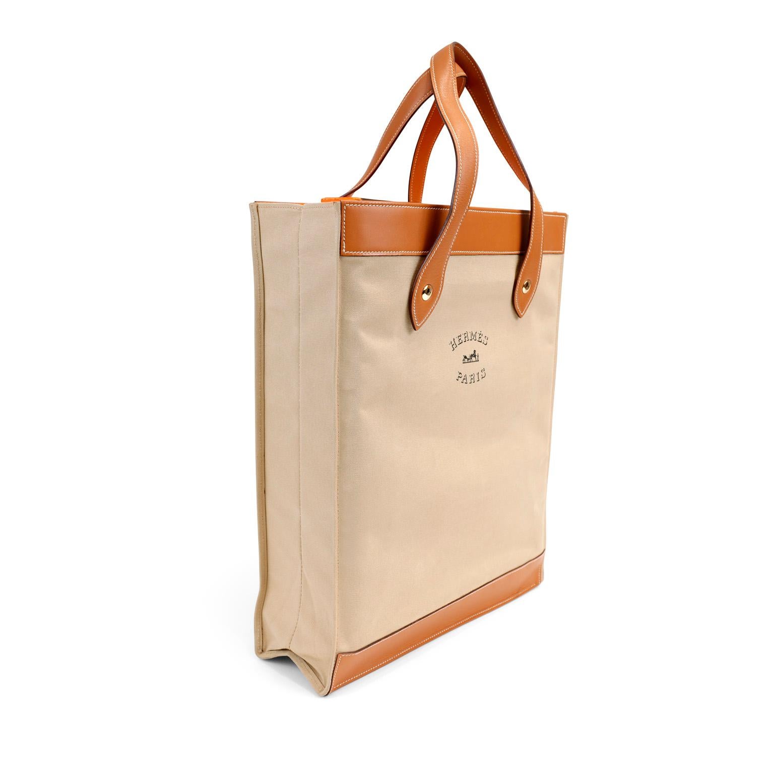 This authentic Hermès Canvas and Gold Swift Leather Unisex Tote is in excellent condition. Neutral beige canvas is supported by sturdy leather bottom, trim and handles. White stitching contrasts beautifully with the saddle colored leather.  
Made in