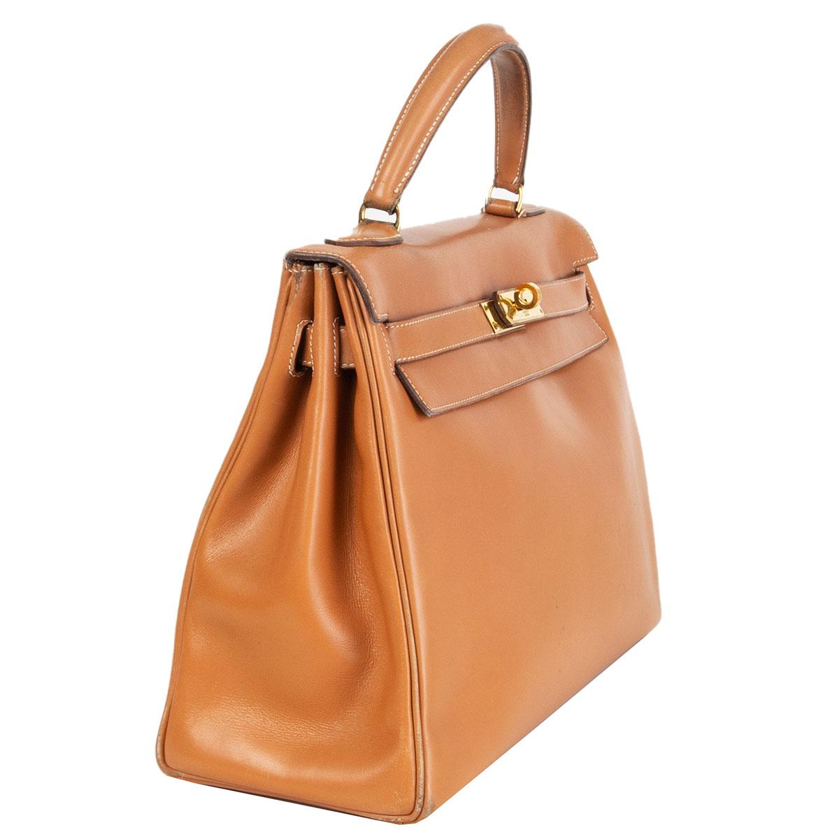 100% authentic Hermes Kelly I 32 Retourne in Natural Box leather with gold-tone hardware. Lined in Chevre (goat skin) with two open pockets against the front and a zipper pocket against the back. Comes with one canvas- and one leather