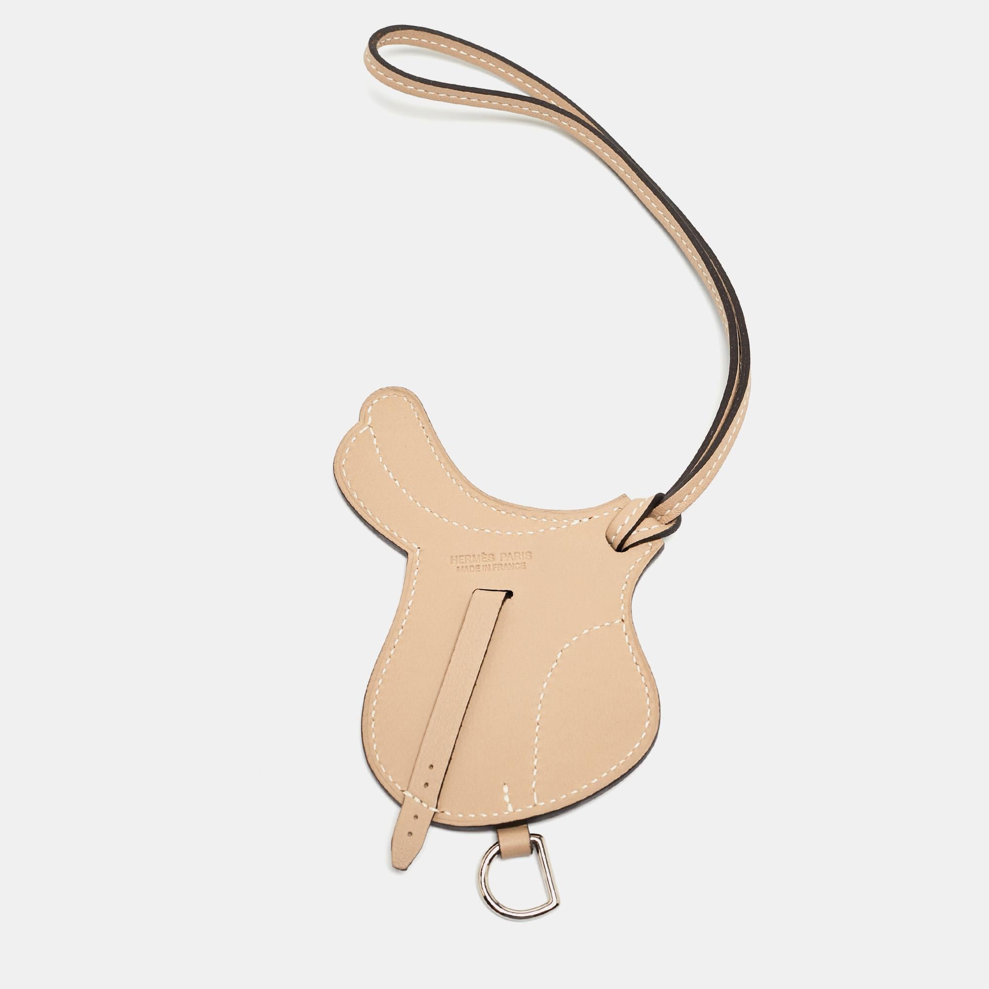The Hermès Paddock Selle bag charm is an exquisite accessory crafted from luxurious Swift Leather. Its design features a luxe beige shade. This charming piece perfectly complements any Hermès bag, adding a touch of elegance and sophistication.

