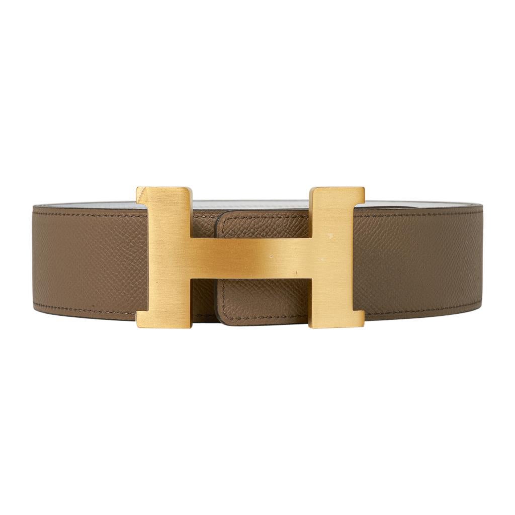 Mightychic offers an  Hermes Constance 42 mm belt featured in reversible Etoupe to White.  
Fabulous over sized brushed gold signature H buckle.  
The 42 mm now a retired size, this is sure to become a collectors treasure. 
Signature HERMES PARIS