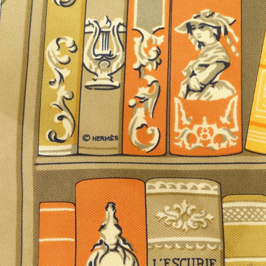Ne manquez pas ce superbe foulard en soie Hermès datant du début du 20e siècle ! Une soie dorée présente une étagère de livres aux tons chauds et neutres qui attire le regard. Remarquez les détails de l'impression jusqu'aux titres des livres, cette