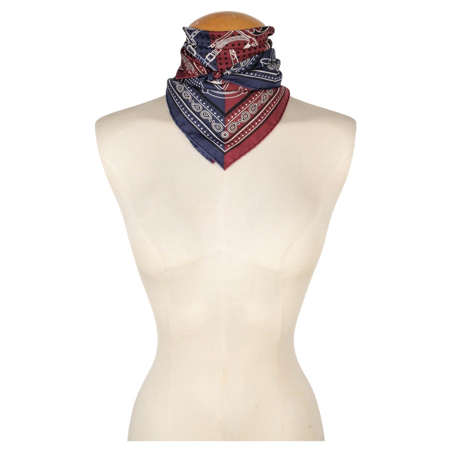 Hermès - (Made in France) Burgundy and blue tone silk 55 squared foulard with the 'big manege' theme designed by Henry d'Origny. Created in 1990.

Additional information:
Condition: Very good condition
Dimensions: 55 cm x 55 cm
Period: 20th