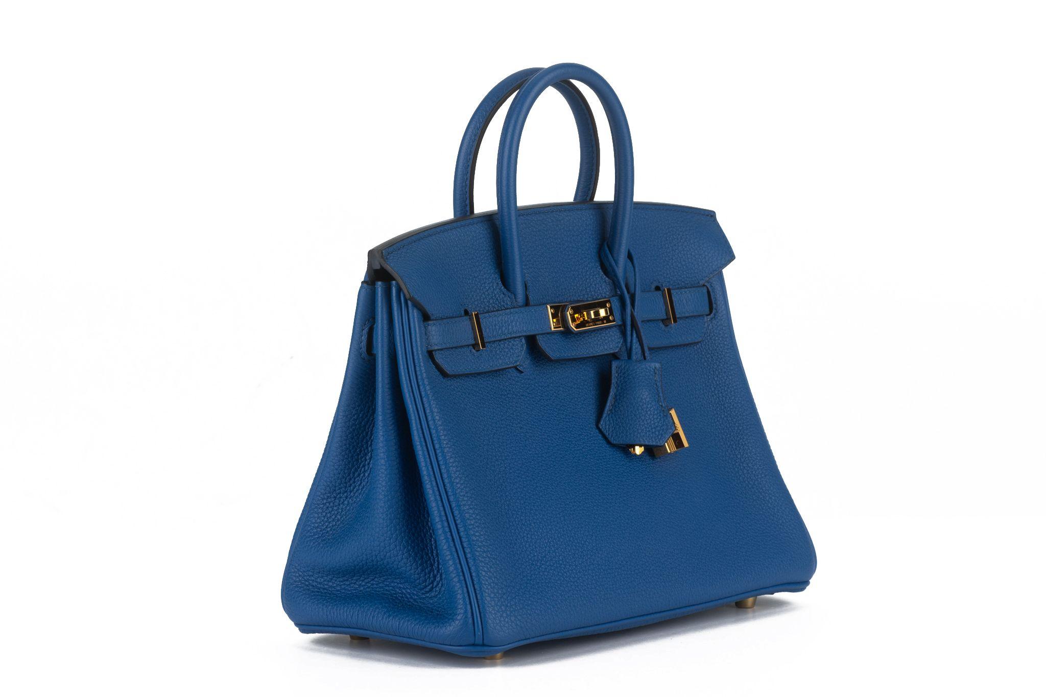 The Birkin 25 in electric blue togo leather with gold hardware and has tonal stitching, front flap, two straps with center toggle closure, clochette with lock and two keys and double rolled handles. The interior is lined with chevre leather.